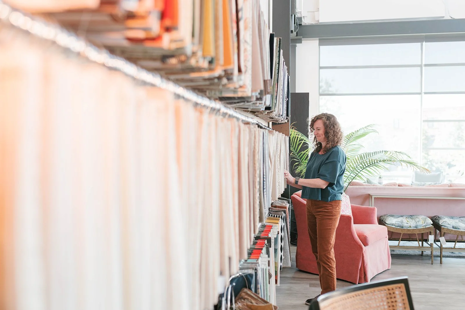Interior designer Cat French in her studio selecting custom fabric swatches from a large wall of fabrics chapel hill interior designer durham interior designer raleigh interior designer
