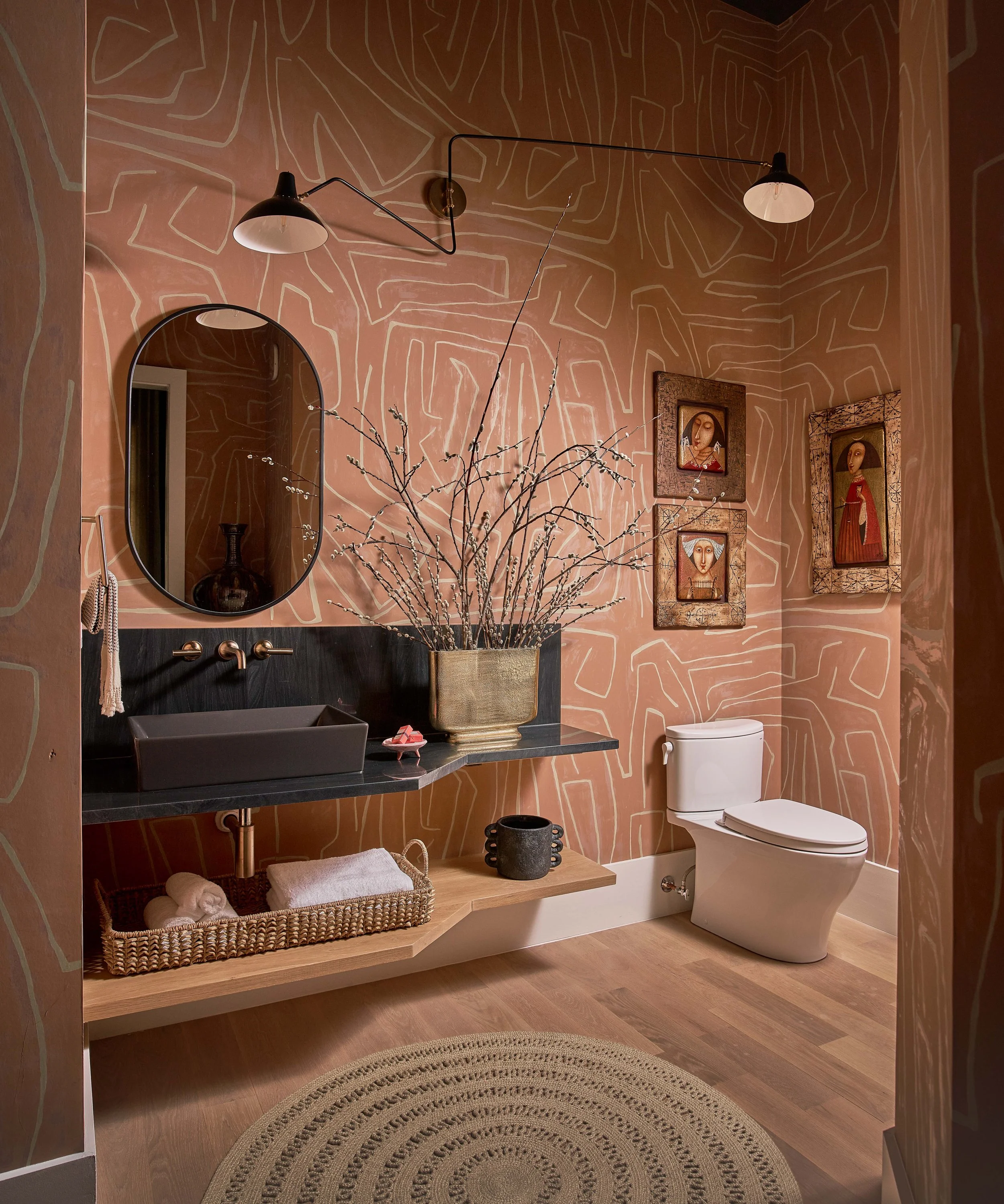 ensuite bathroom with terra cotta walls modern wallpaper design black quartzite vanity with open shelving and asymmetrical light fixture luxury bathroom design cat french design durham interior designer luxury design firm north carolina