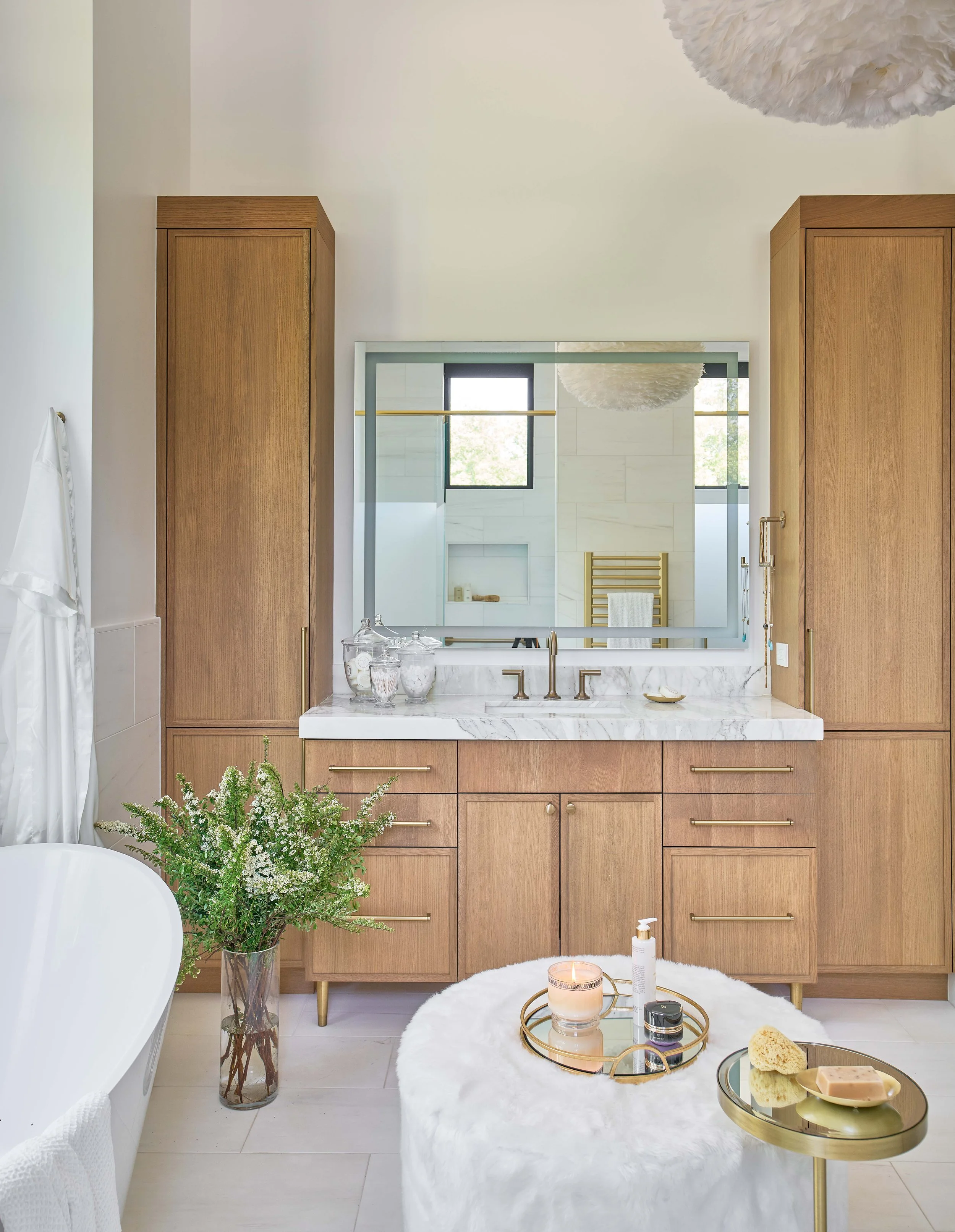 primary bathroom vanity with custom cabinetry and carrara marble countertop and lighted mirror luxury bathroom design by cat french design durham interior designer chapel hill interior designer elevated interior design custom home design
