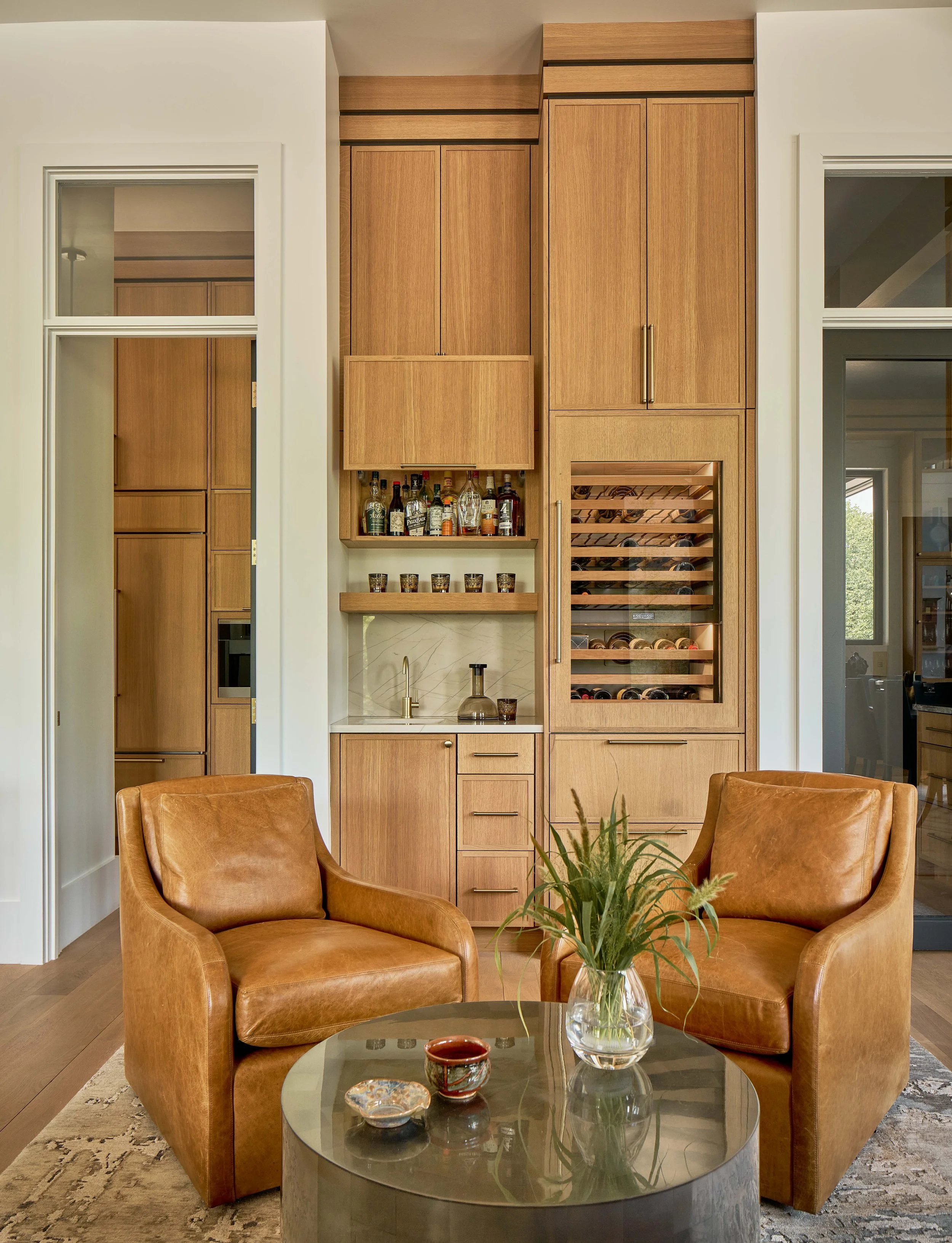 cognac leather swivel chairs and coffee table with custom built-in bar wine fridge custom cabinetry with gold hardware luxury custom home durham nc durham interior design firm cat french design comfortable luxury interior design
