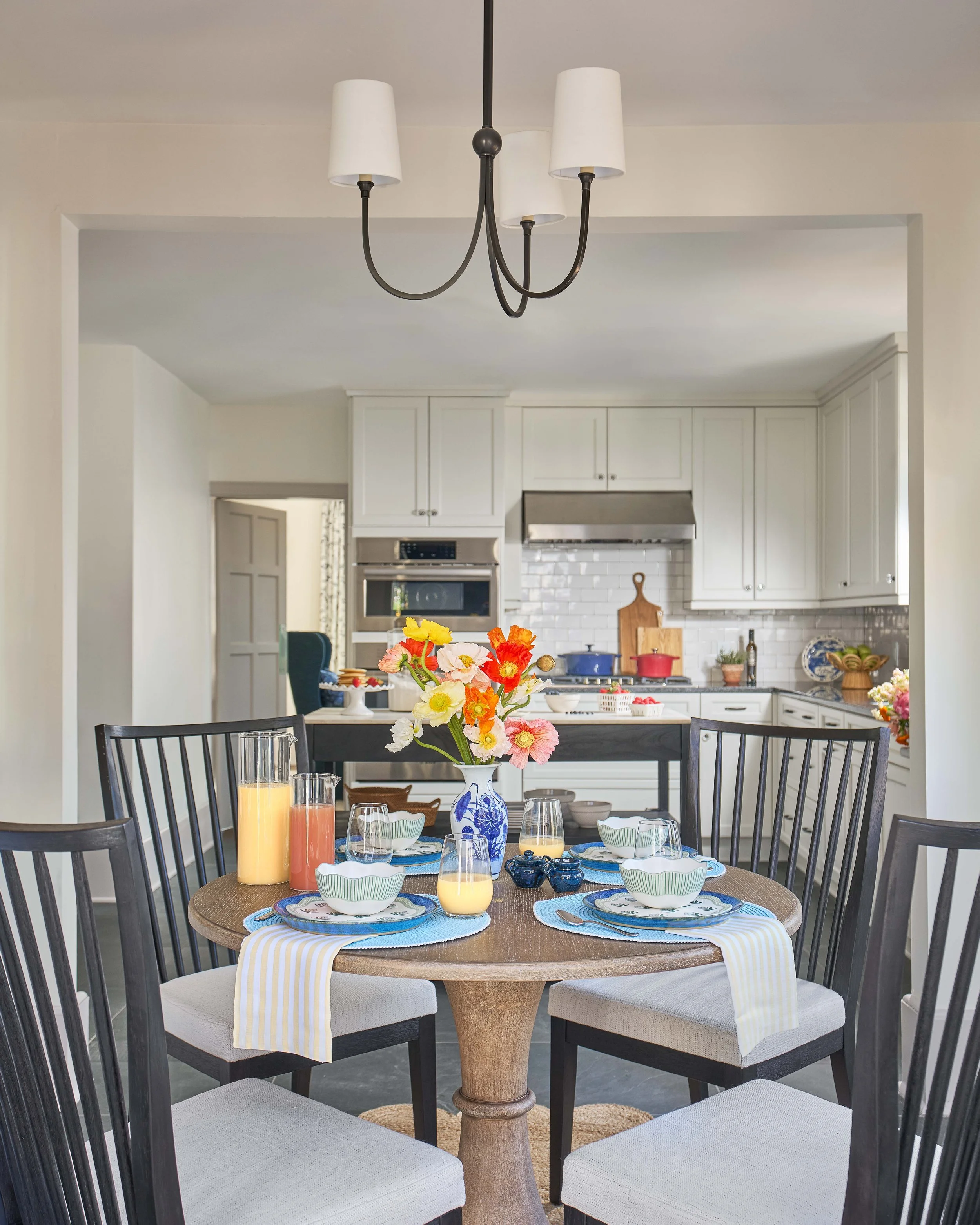circular dining table in breakfast nook looking into renovated kitchen designed by cat french design chapel hill interior designer durham interior designer