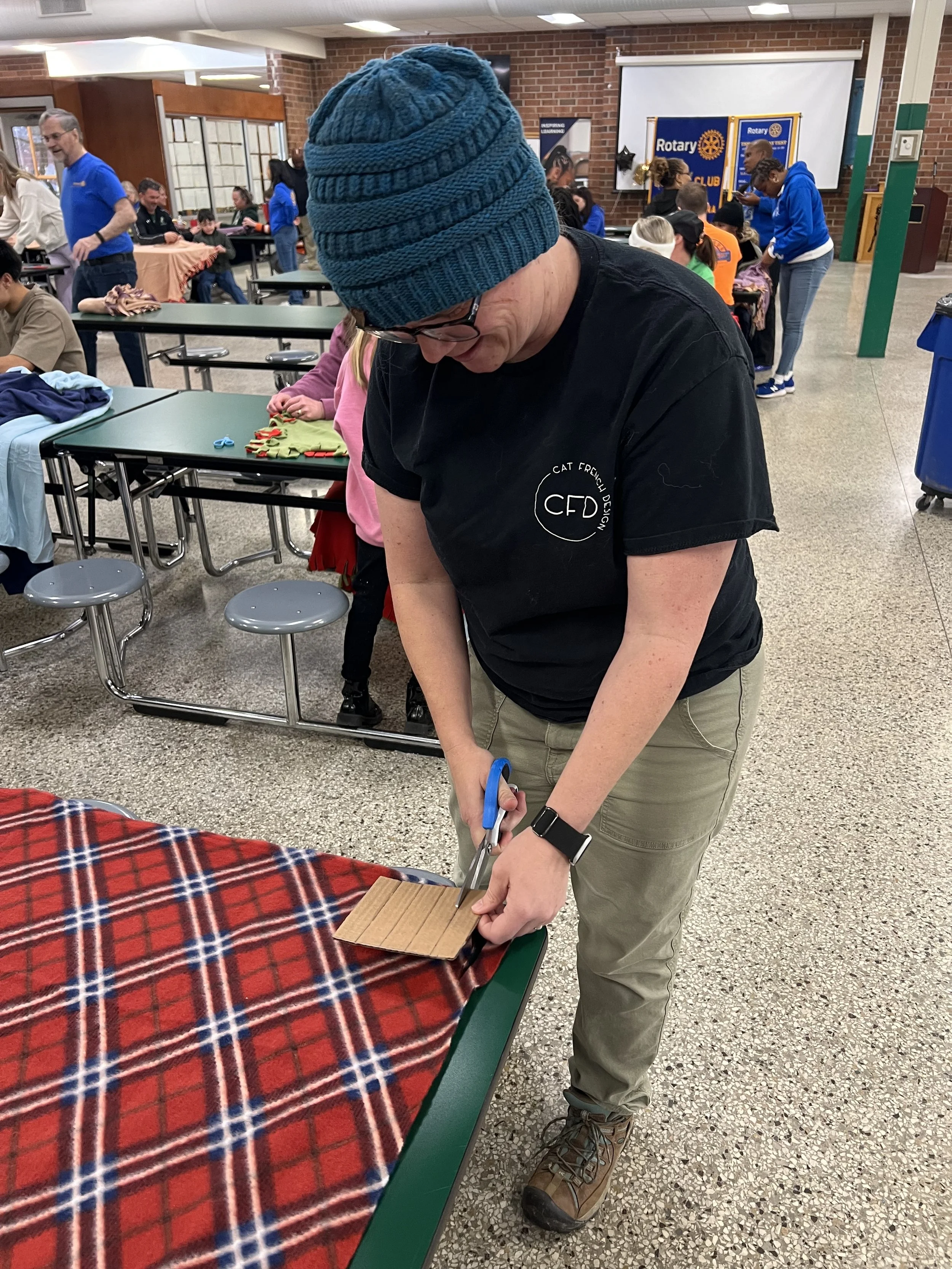 Cat French Design team member Ryan cutting fabric for blankets to deliver to seniors in need pittsboro chapel Hill interior designer