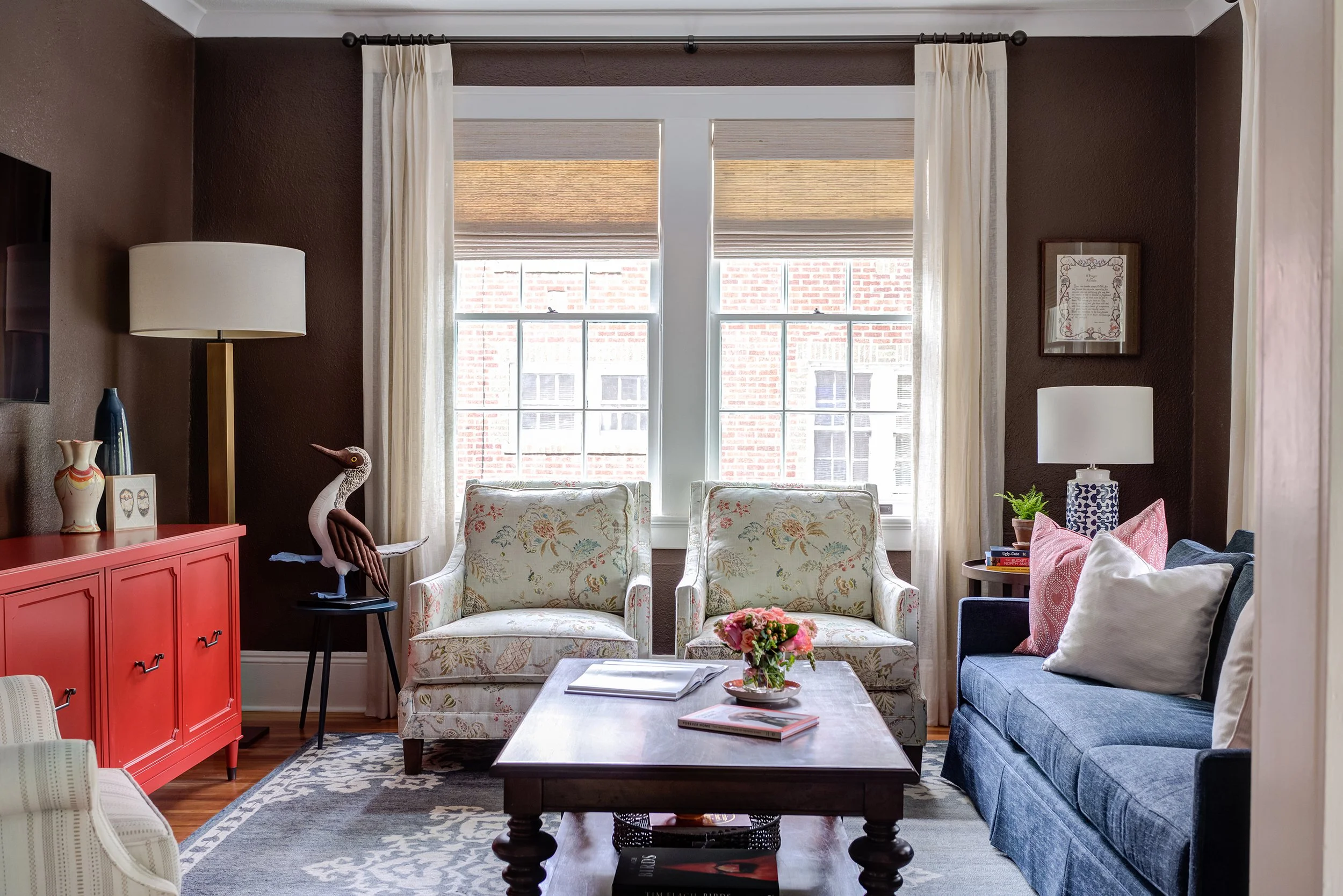 a cozy den living room with chocolate brown walls blue couch and red console historic chapel hill home designed by cat french design chapel hill interior designer durham interior designer