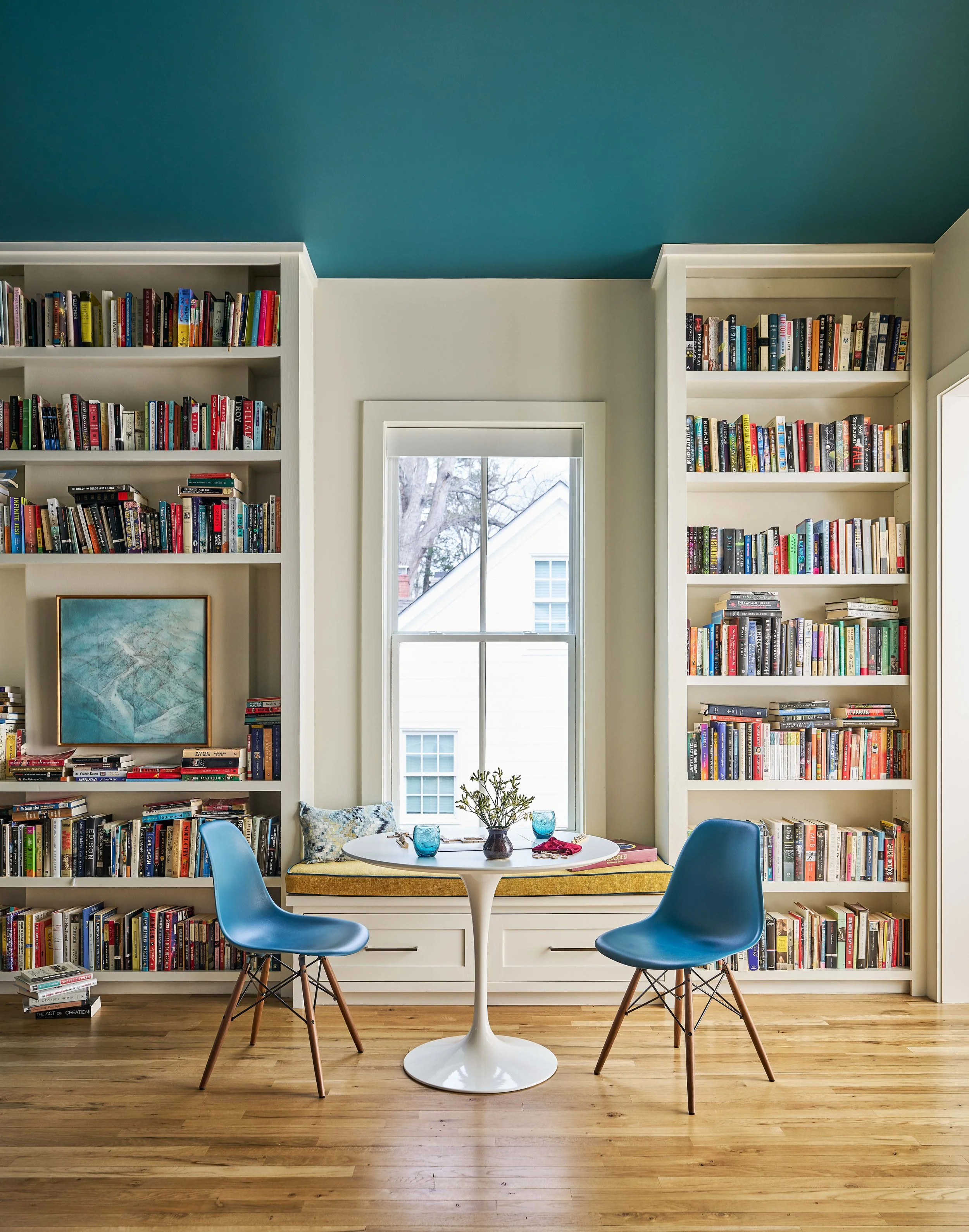 sunny breakfast nook with built-in bench and custom floor to ceiling bookshelves with teal ceiling mid-century modern kitchen design luxury interior designer Chapel Hill, nc homes with personality interior design