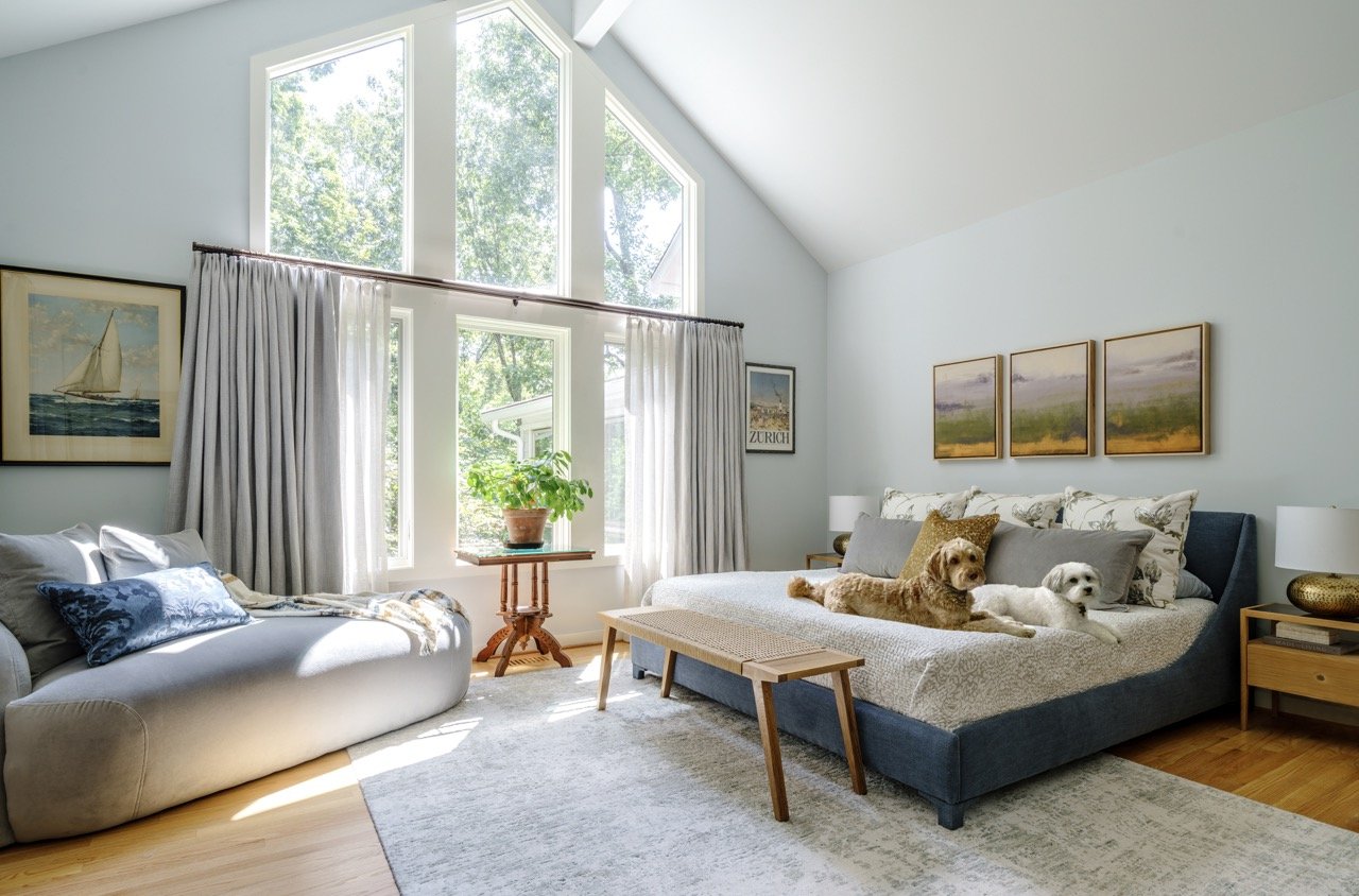 two doodle dogs laying on a bed in a sunny mid century modern bedroom designed by cat french design award winning chapel hill interior designer