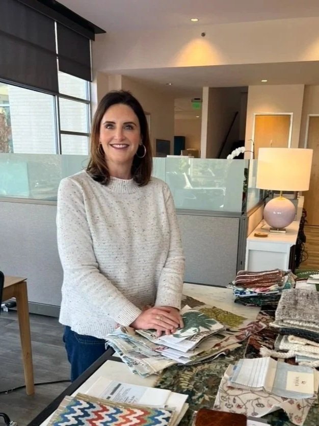 rebecca thurston lead designer at cat french design award winning chapel hill interior designer standing by a table full of custom fabric samples in their interior design studio in southern village