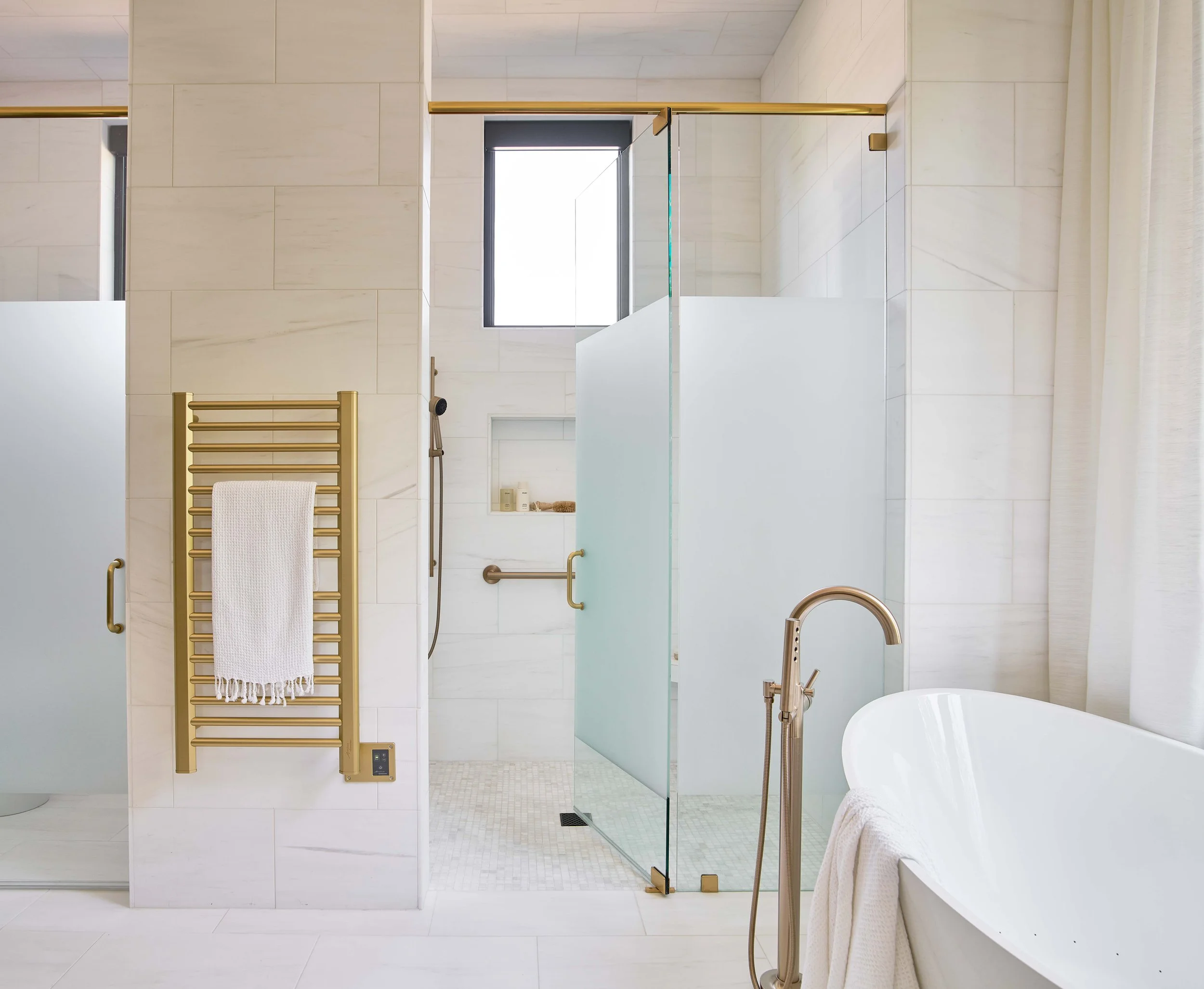 primary bathroom design white tile floating tub gold heated towel rack floor to ceiling tile and modern gold hardware glass shower door in a durham luxury estate home design by cat french design luxury home designer chapel hill nc