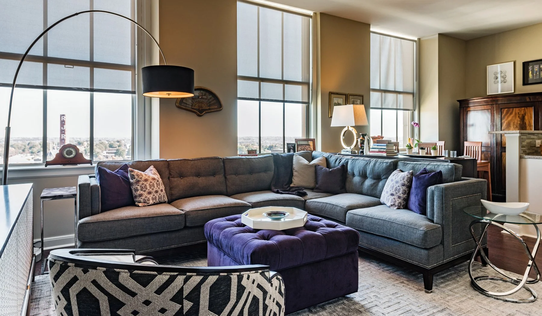 living room of a large apartment with gray sectional couch patterned club chair and indigo ottoman designed by cat french design chapel hill interior designer durham interior designer award winning interior design chapel hill
