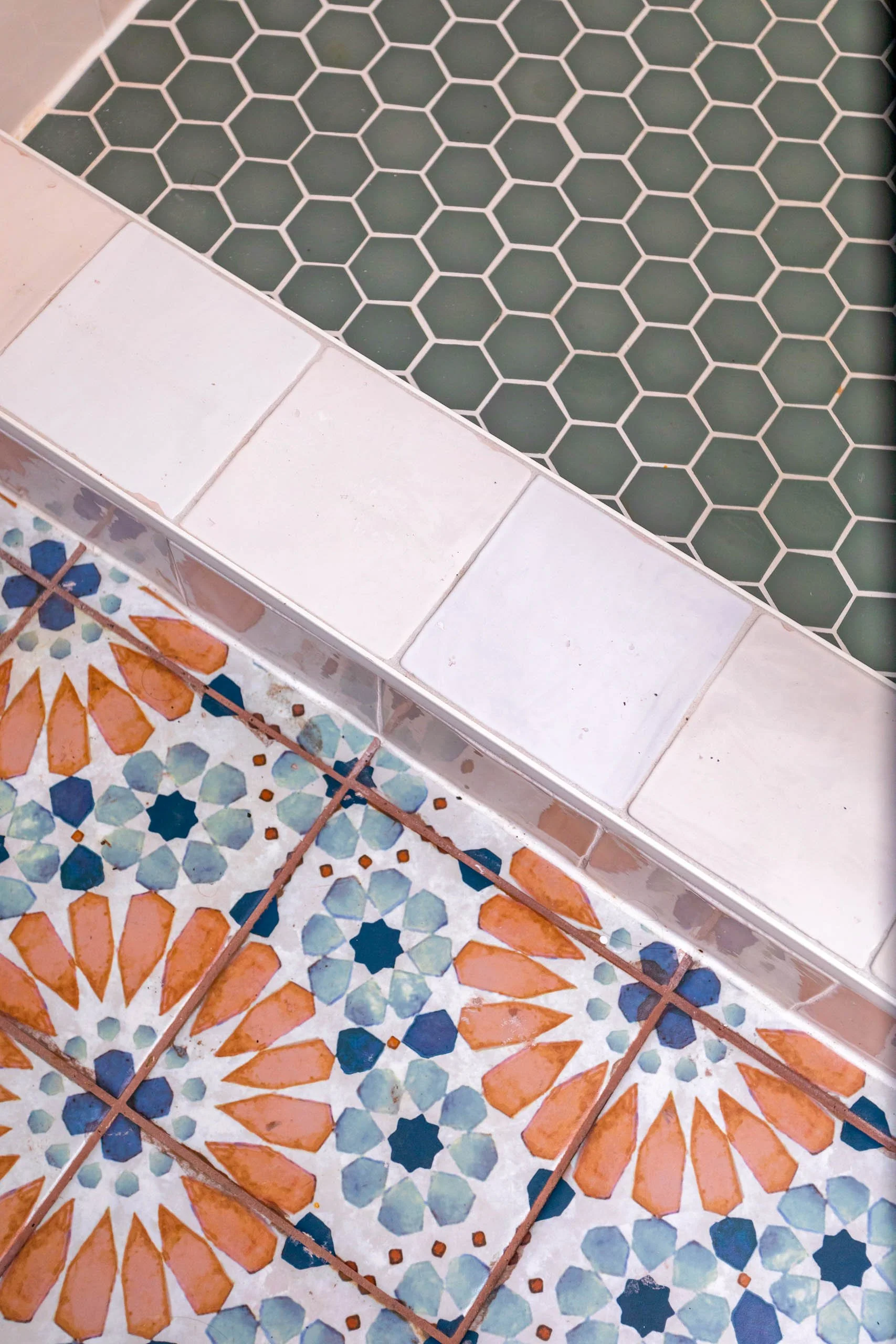 colorful tile with light and dark blue with terracotta floral pattern and earthy green hex tile in a colorful bathroom design by cat french design in a chapel hill home design