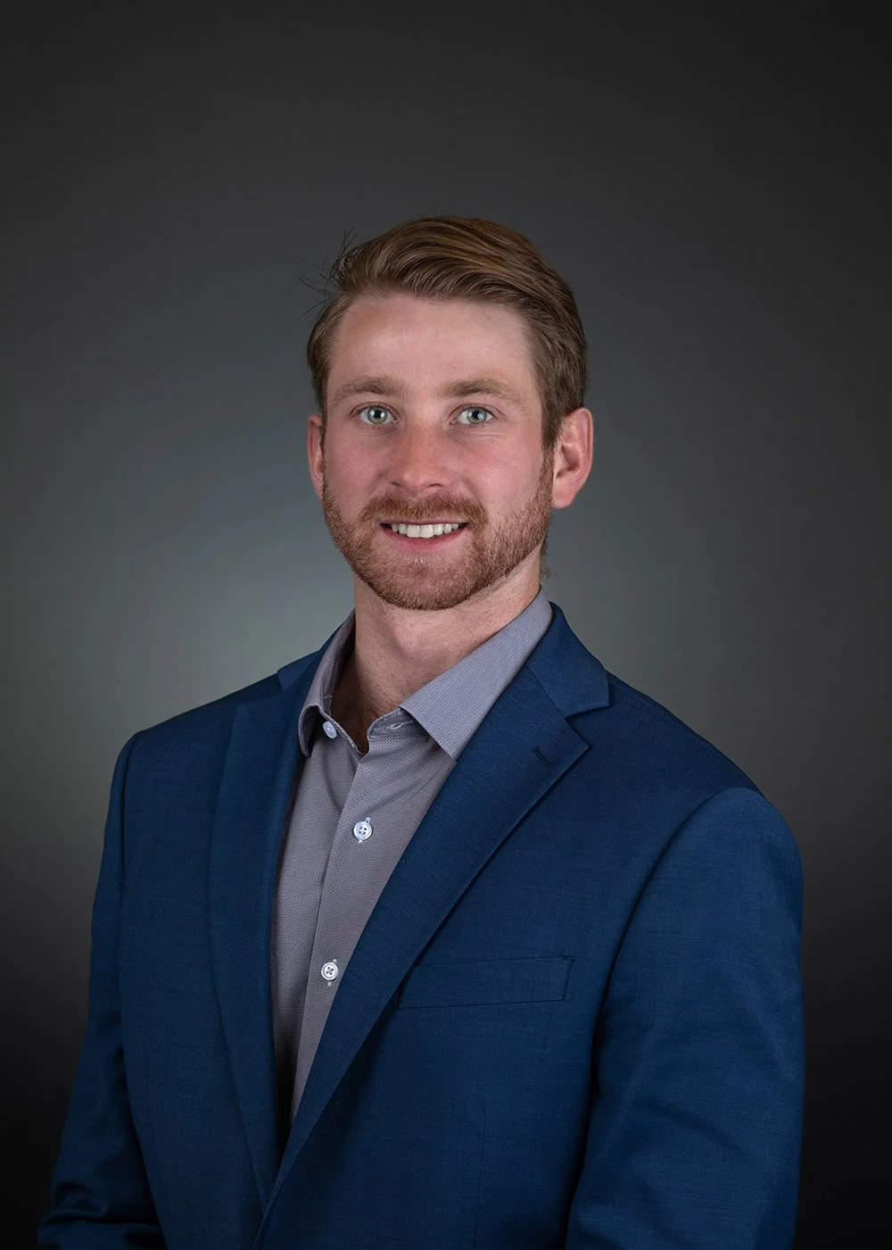 Silhouette of a faceless person wearing a suit and tie on a gray background.