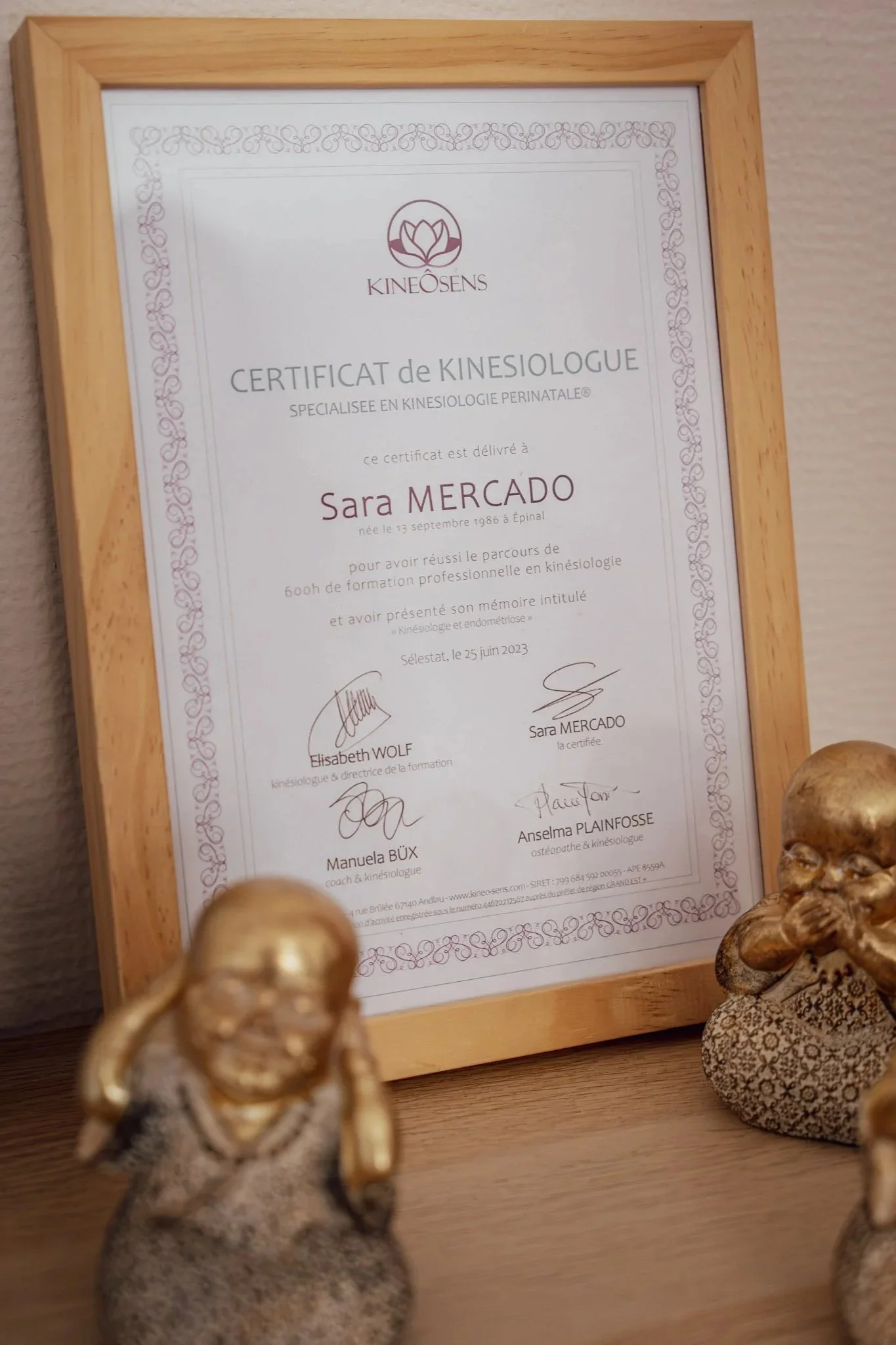 Un diplôme de kinésiologie posée sur un meuble avec des statue de Bouddha relaxante