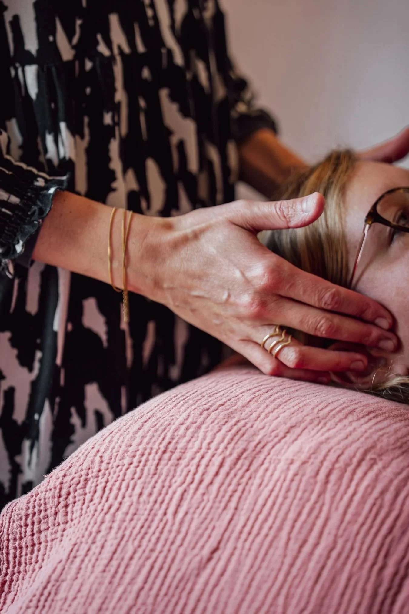 Une femme pose ses doigts sur la tête d'une femme allongée sur une table de kinésiologie