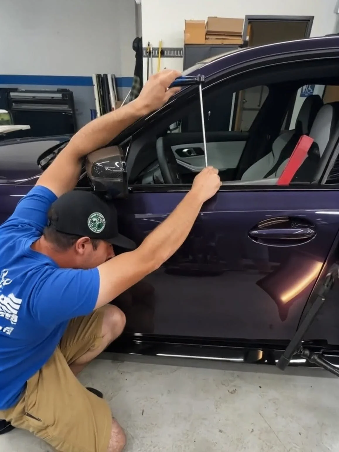 A mobile dent repair technician using specialized tools to perform paintless dent removal on a car.