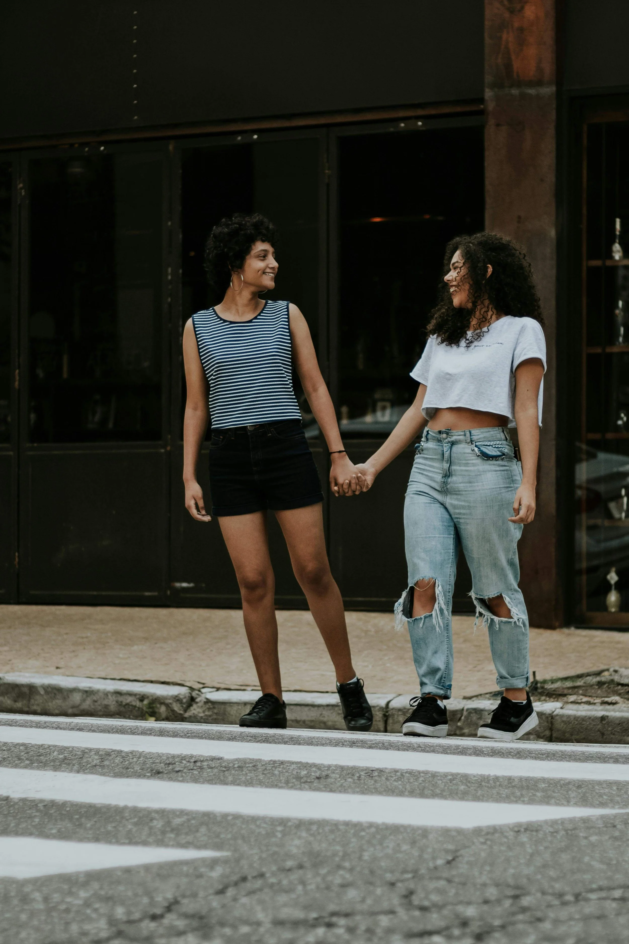 Two women holding hands while crossing a street