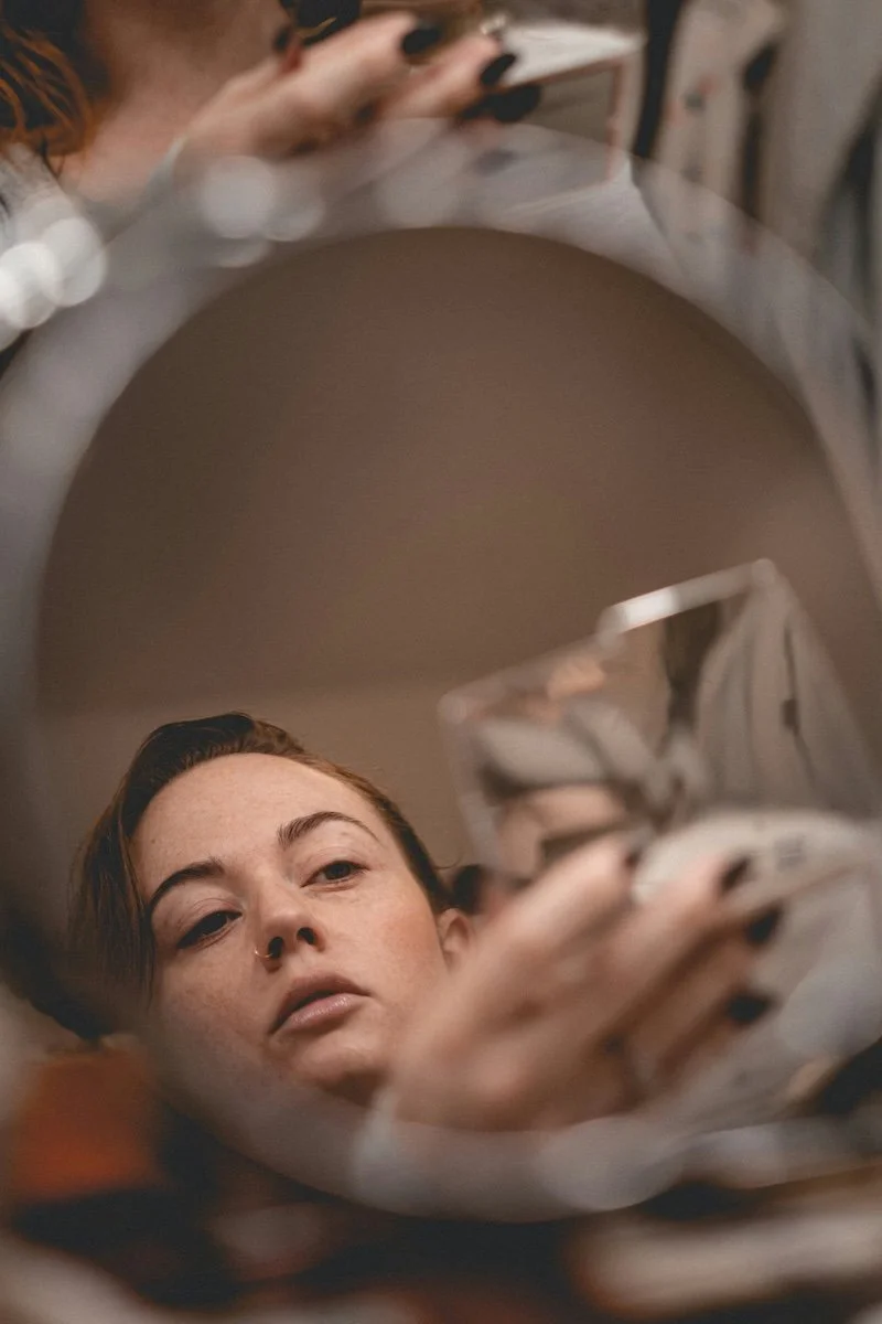 woman looking at her reflection in soft natural light