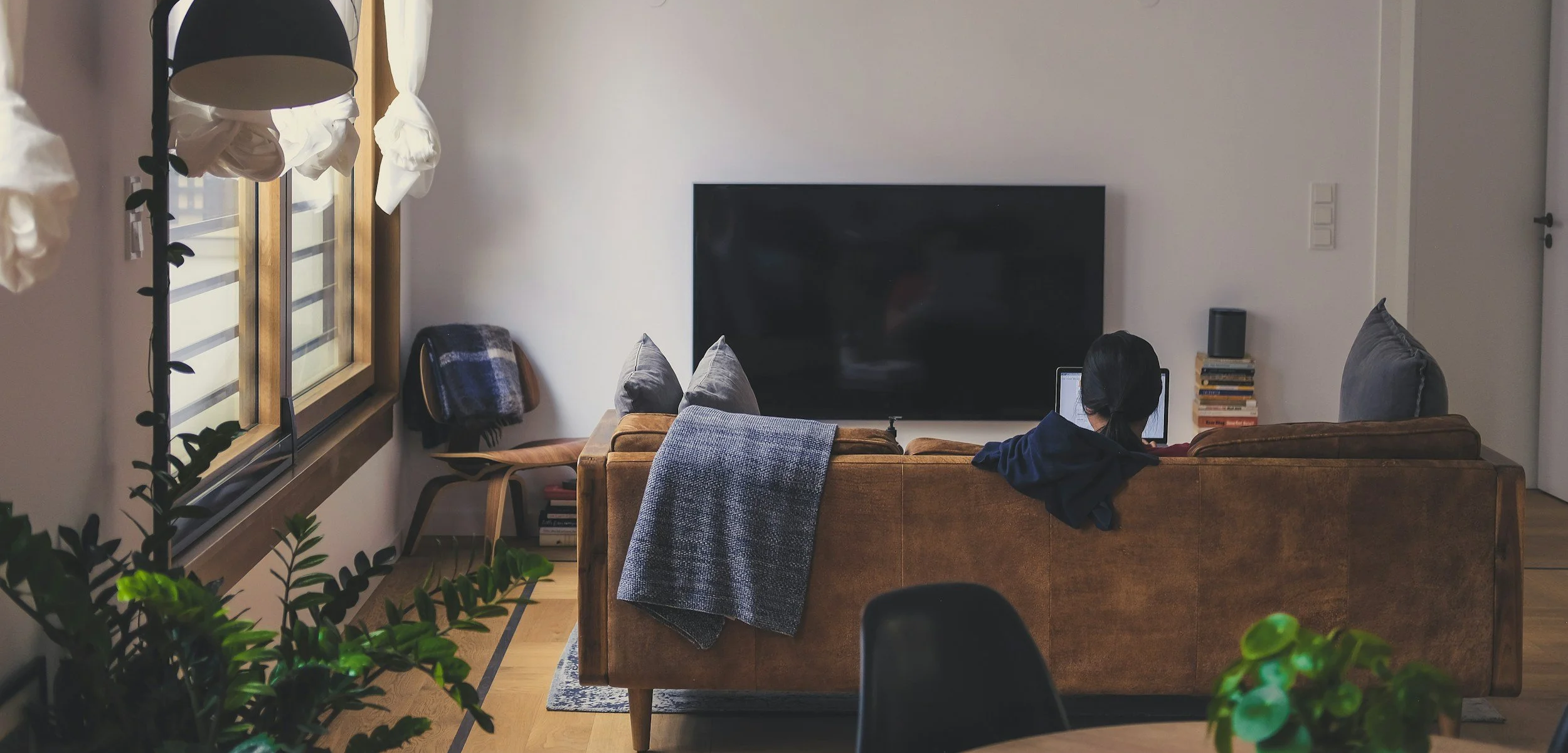 Person sitting on couch using laptop in their apartment.