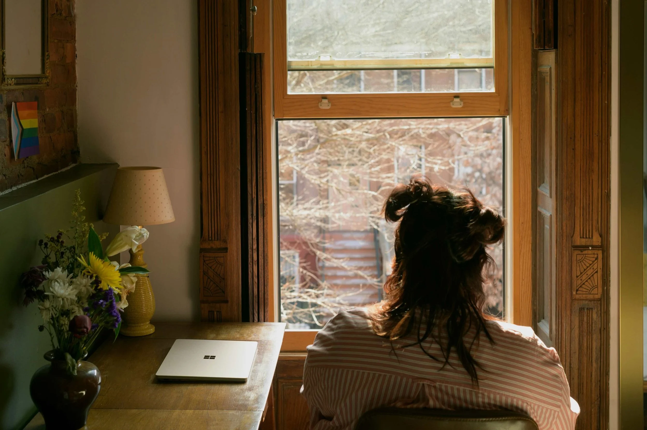 Person looks out of window on brownstone lined street