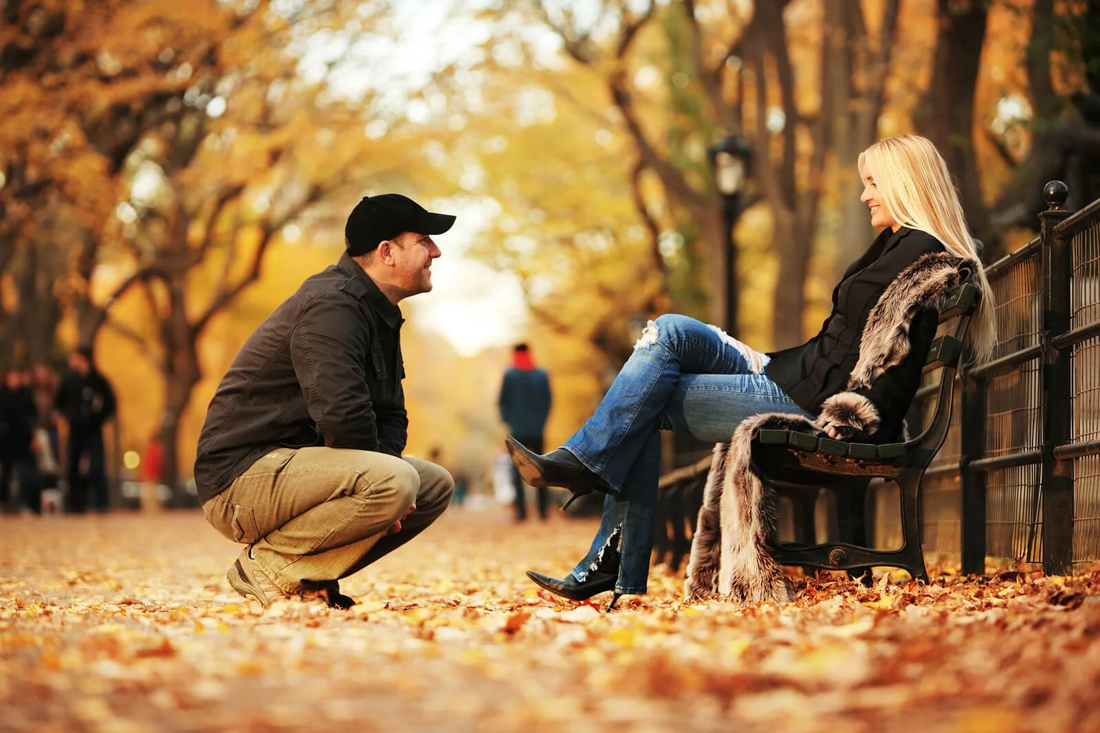A couple together with one person sitting on a bench