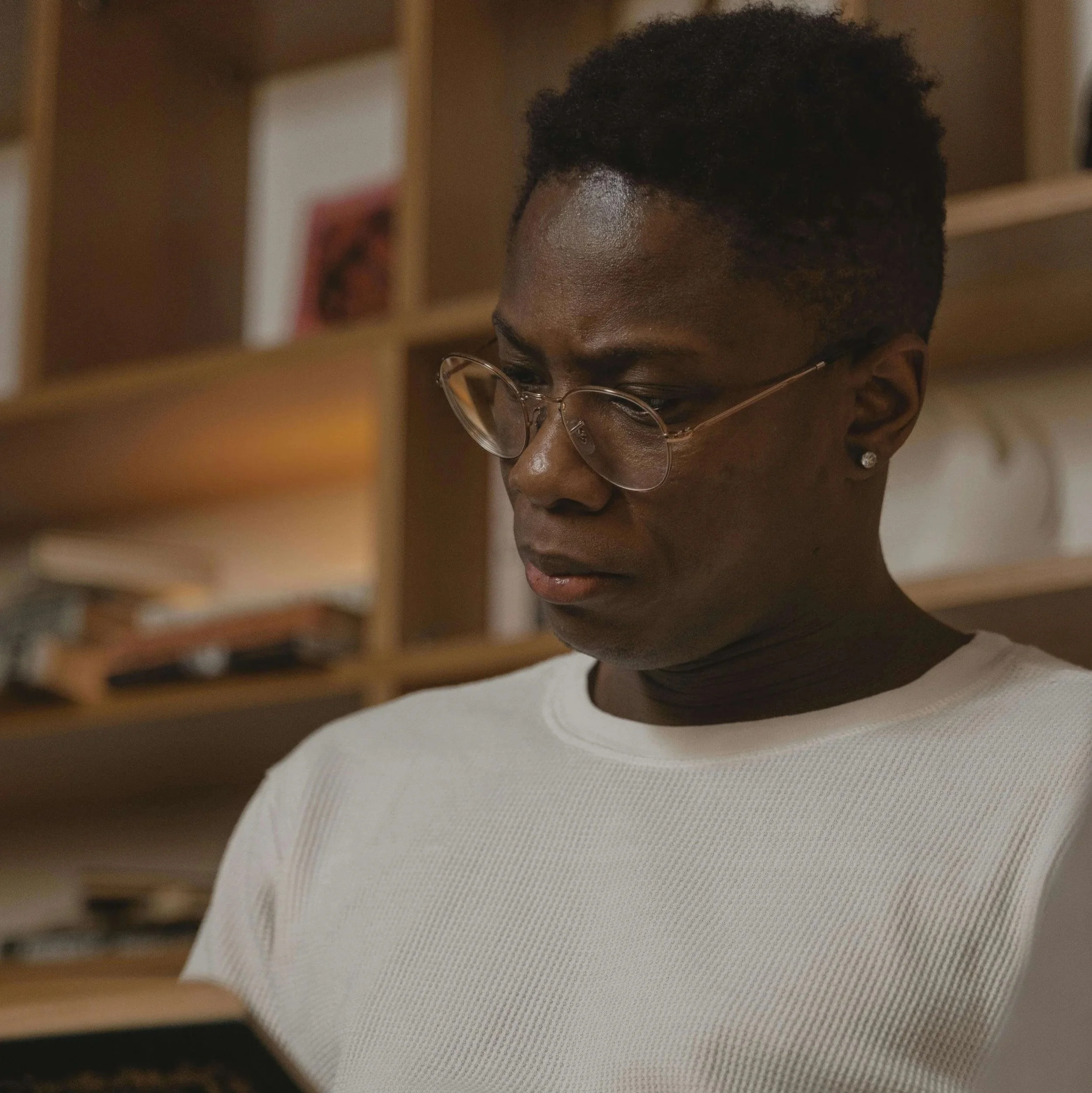 A person wearing glasses writing in a notebook in a warmly lit room
