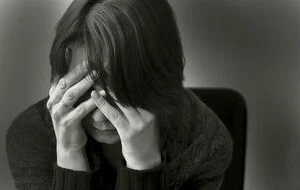Black and white image of a woman with her hands over her face