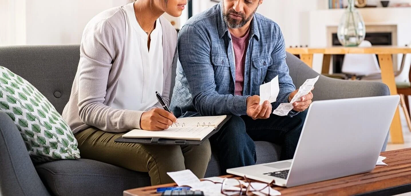 A couple sitting together looking at papers and writing in a notebook