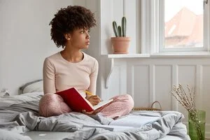 A woman sitting on a bed journaling