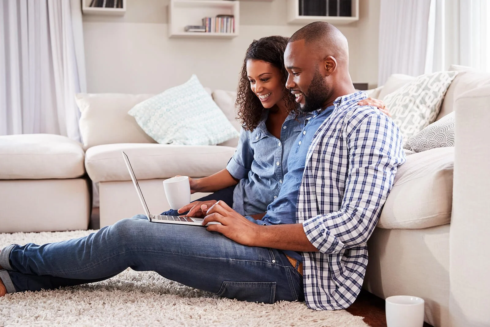 A couple sitting on the floor with an open laptop ready for an online therapy session