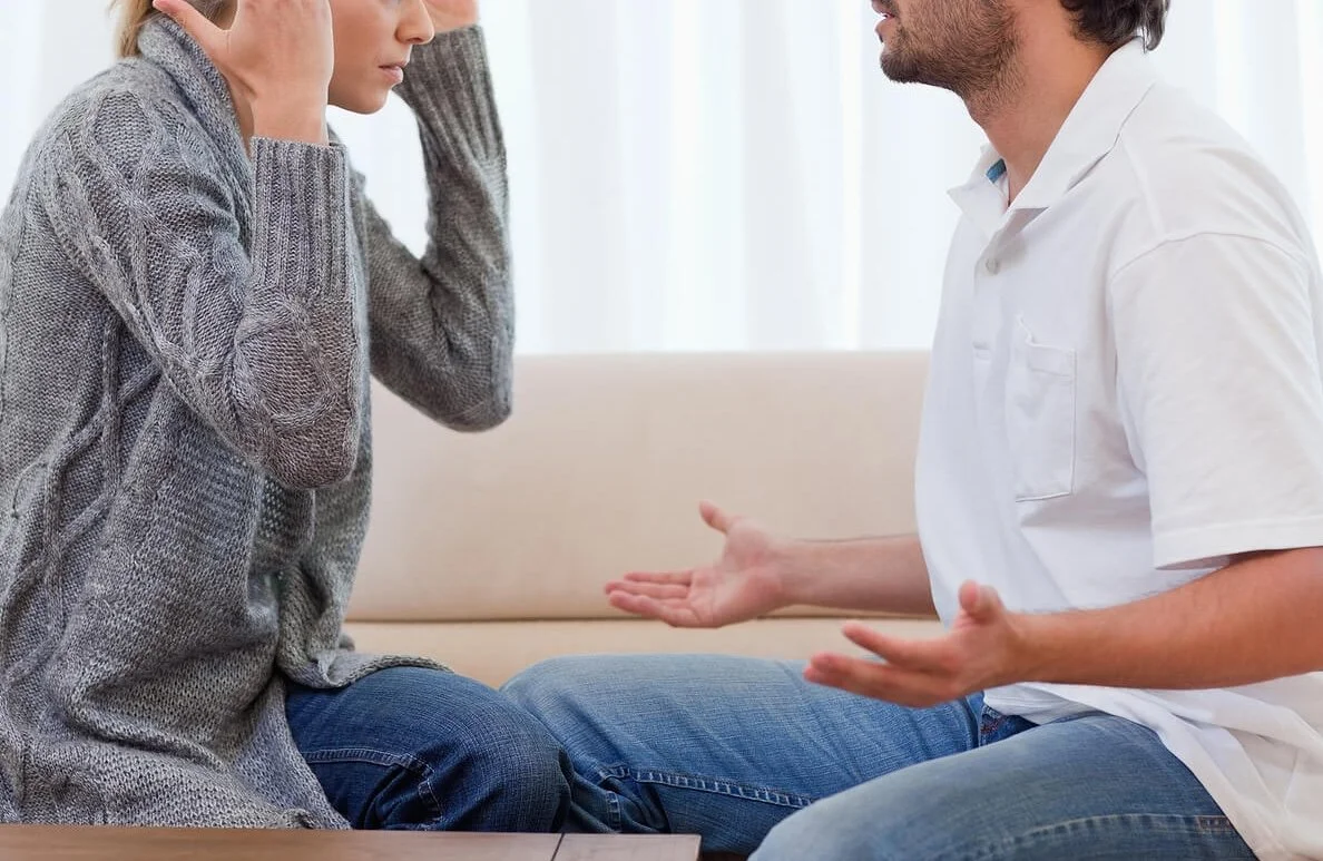 A couple sitting apart from each other, looking tense