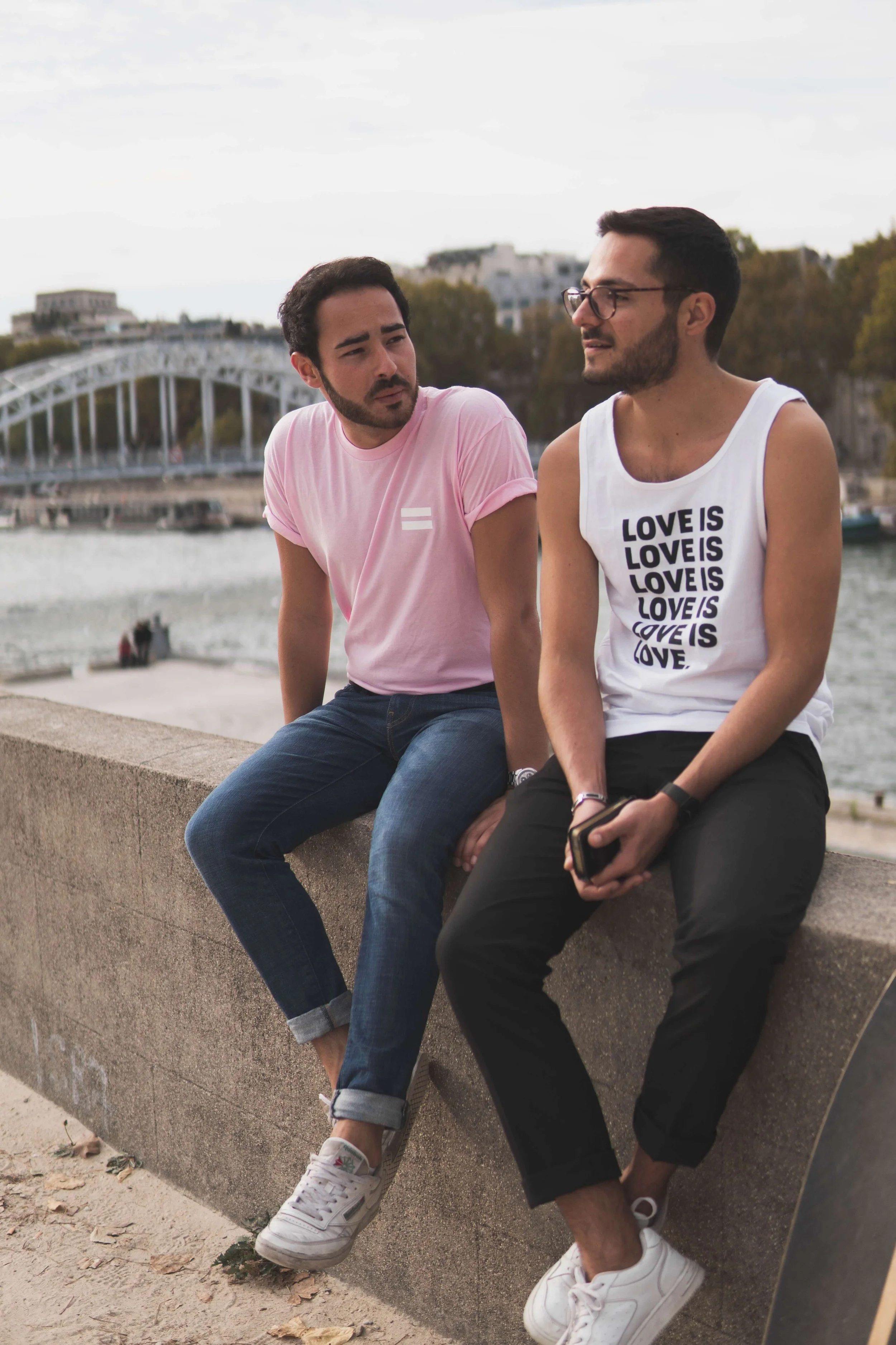 Two men sitting together on a low wall outdoors