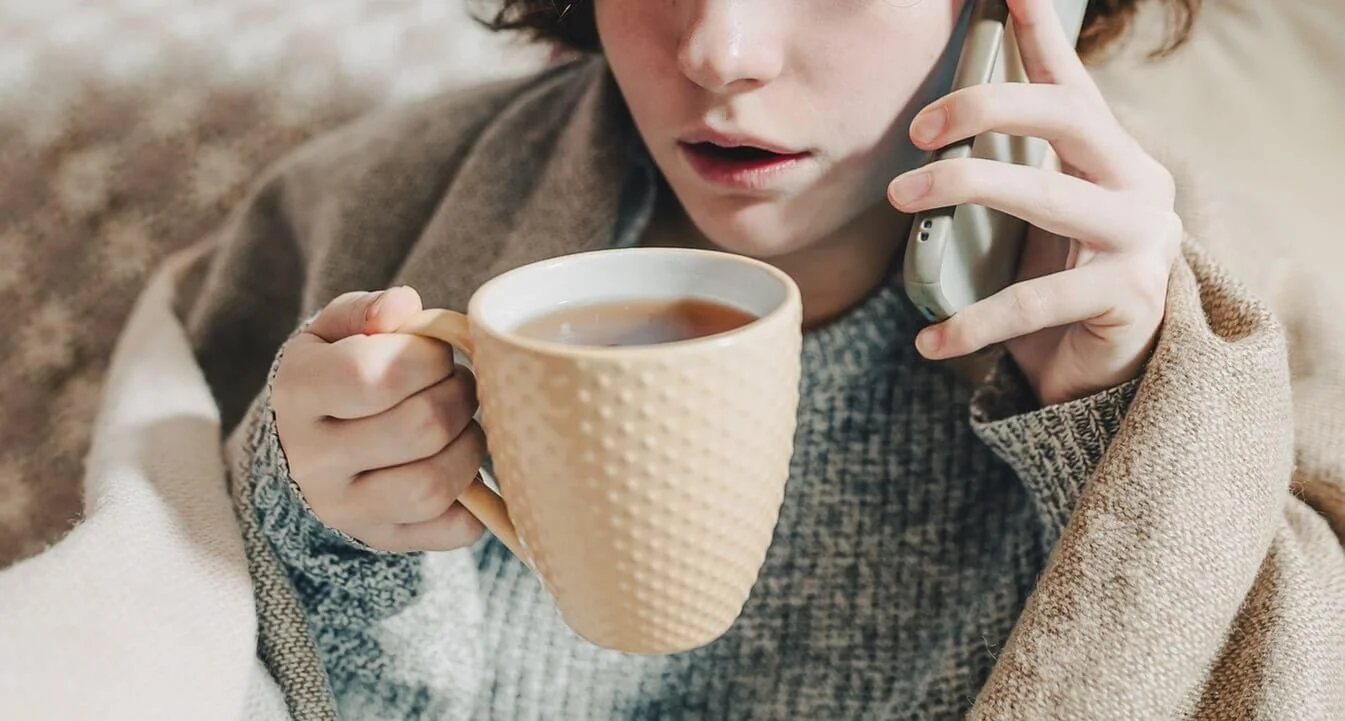 A young woman drinking tea while on the phone