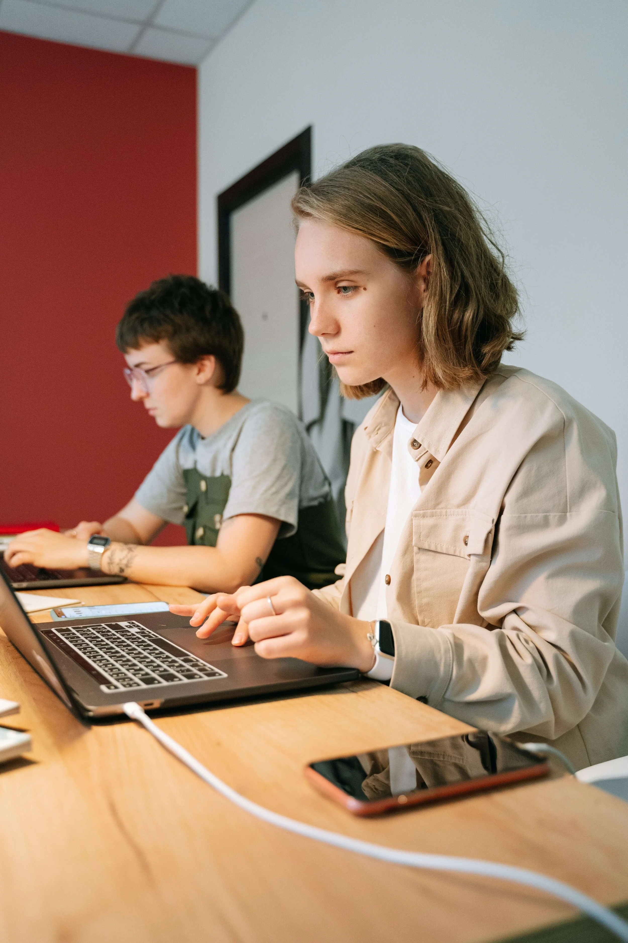 A person working on a lap at a desk next to another person