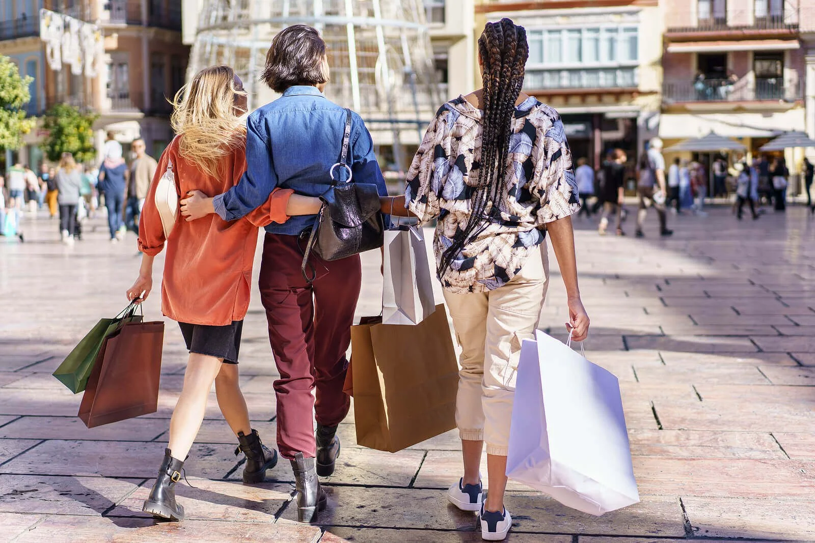 Three women with shopping bags walking together outside