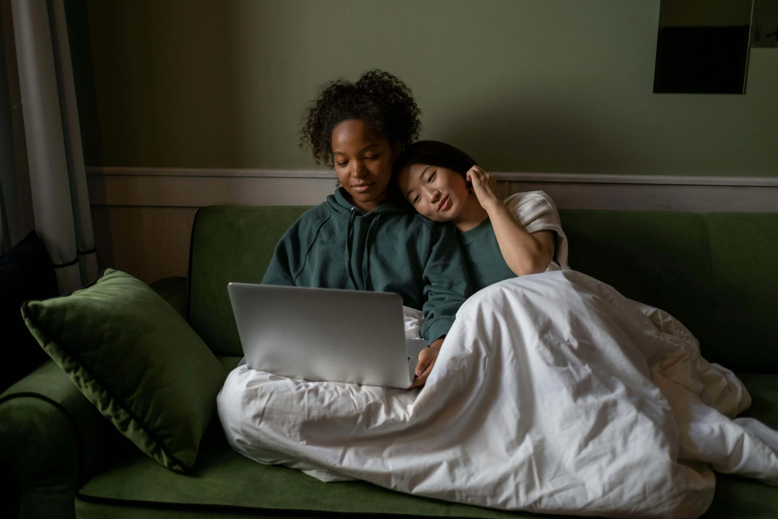 A couple sitting on a couch with a laptop open set up for an online therapy session