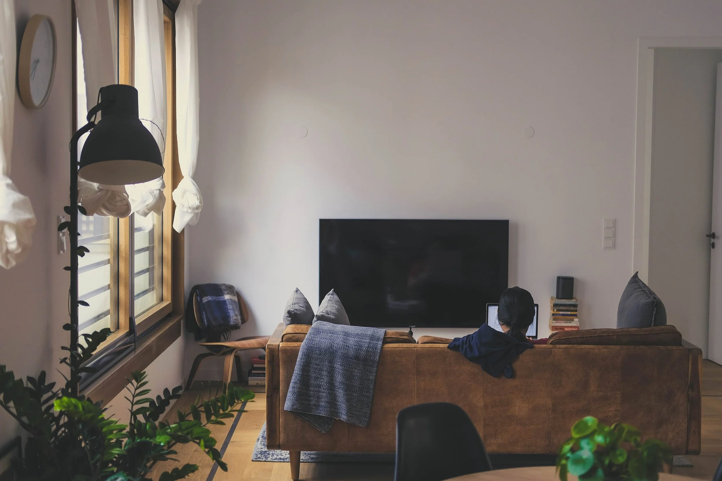 Person sitting on couch using laptop in their apartment.