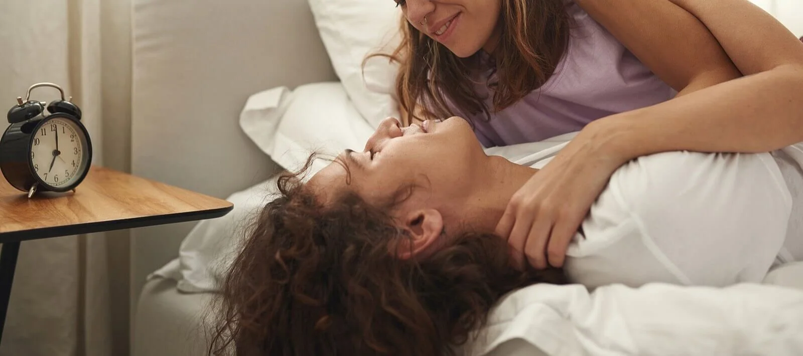 A couple lying in bed smiling at each other