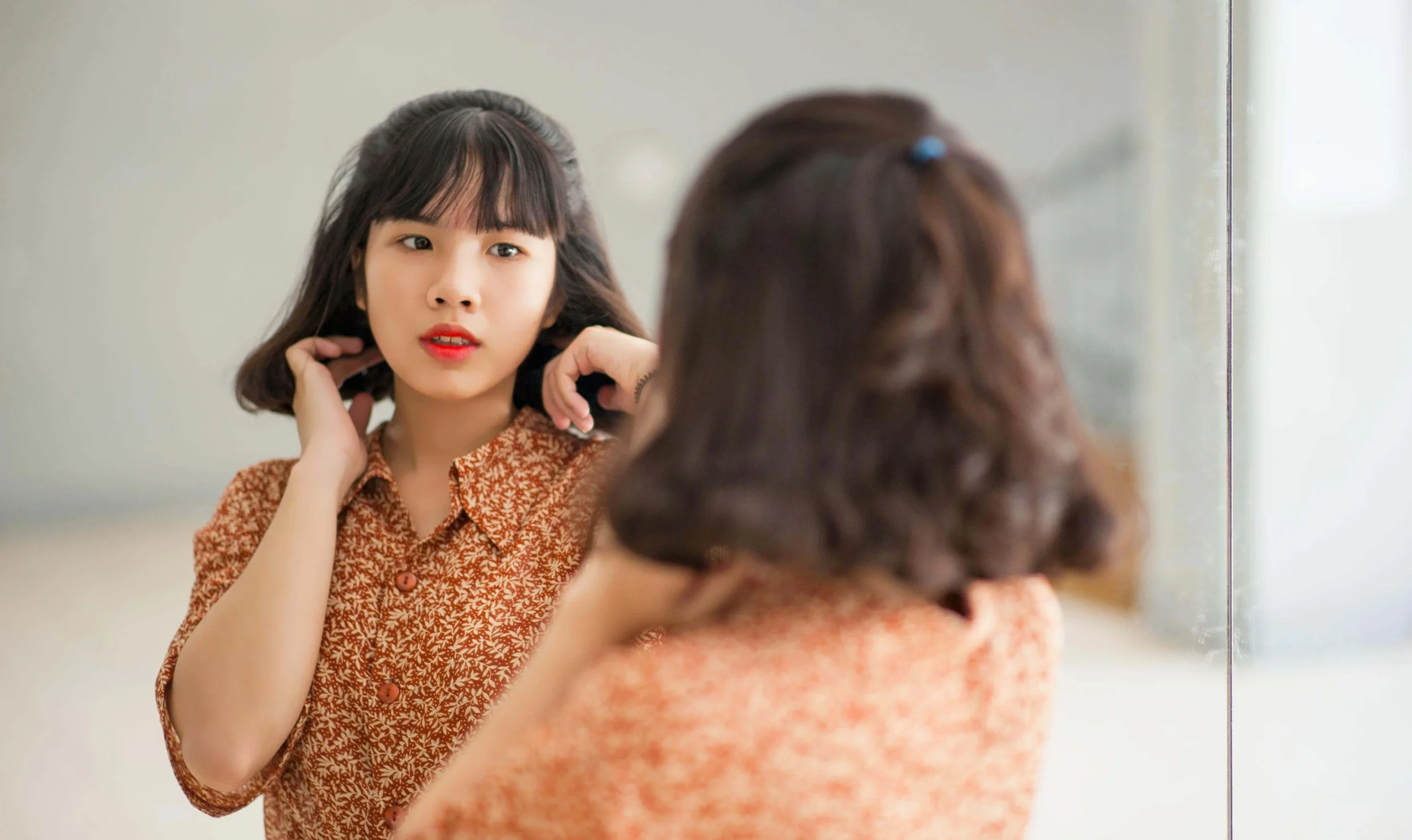 A woman looking at her reflection in a mirror with a thoughtful expression