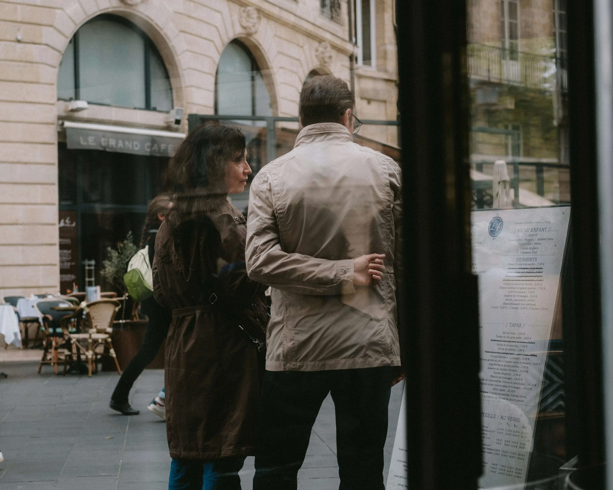 A couple looking at a menu together on a city street