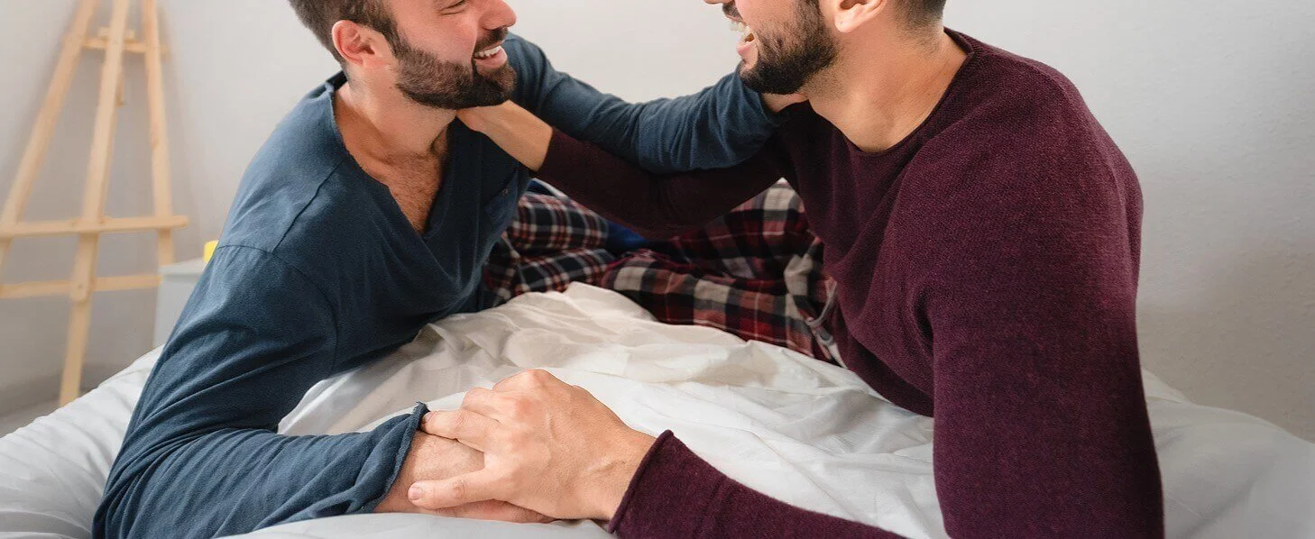 A couple lying in bed smiling at each other