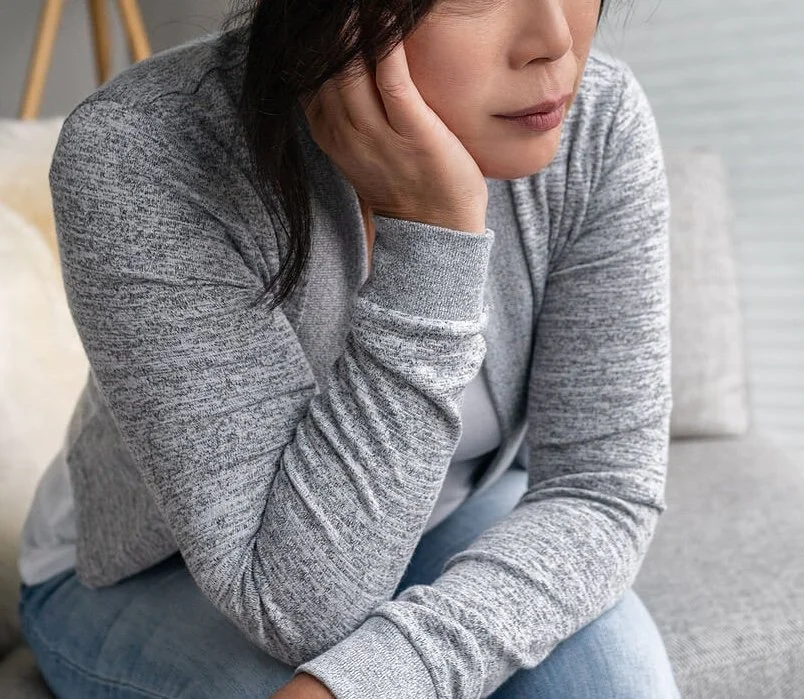 A woman sitting alone, looking anxious