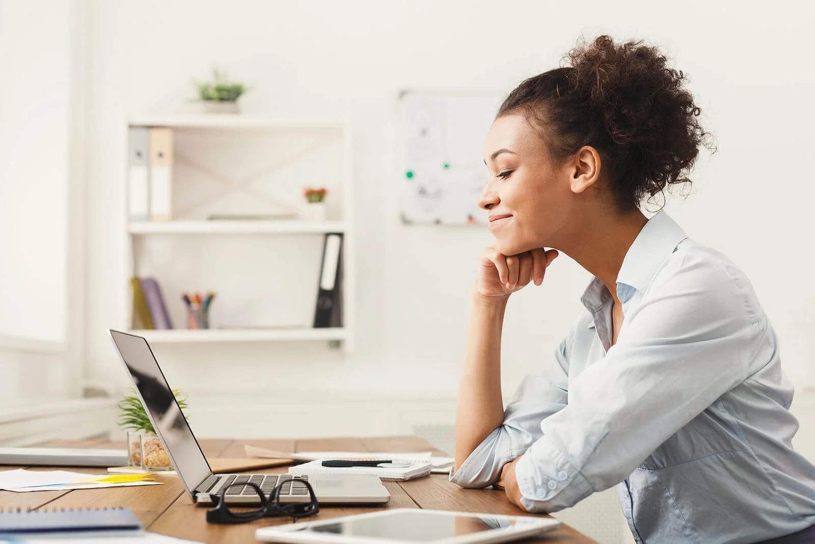 A woman smiling at her laptop at a desk