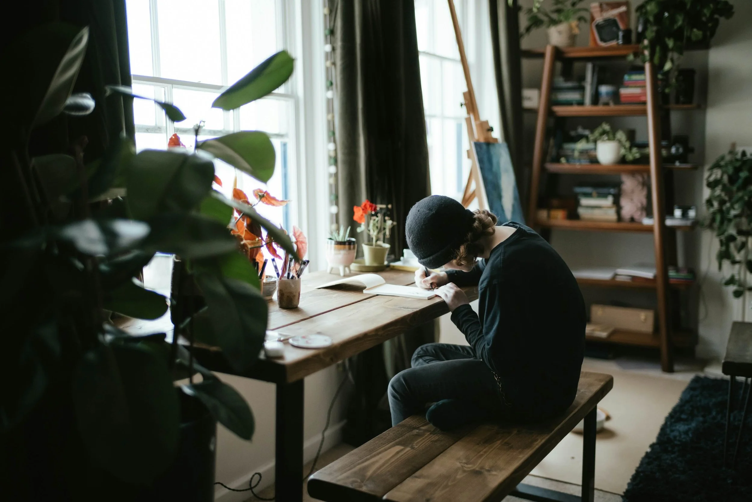 Person writes at a table in a studio