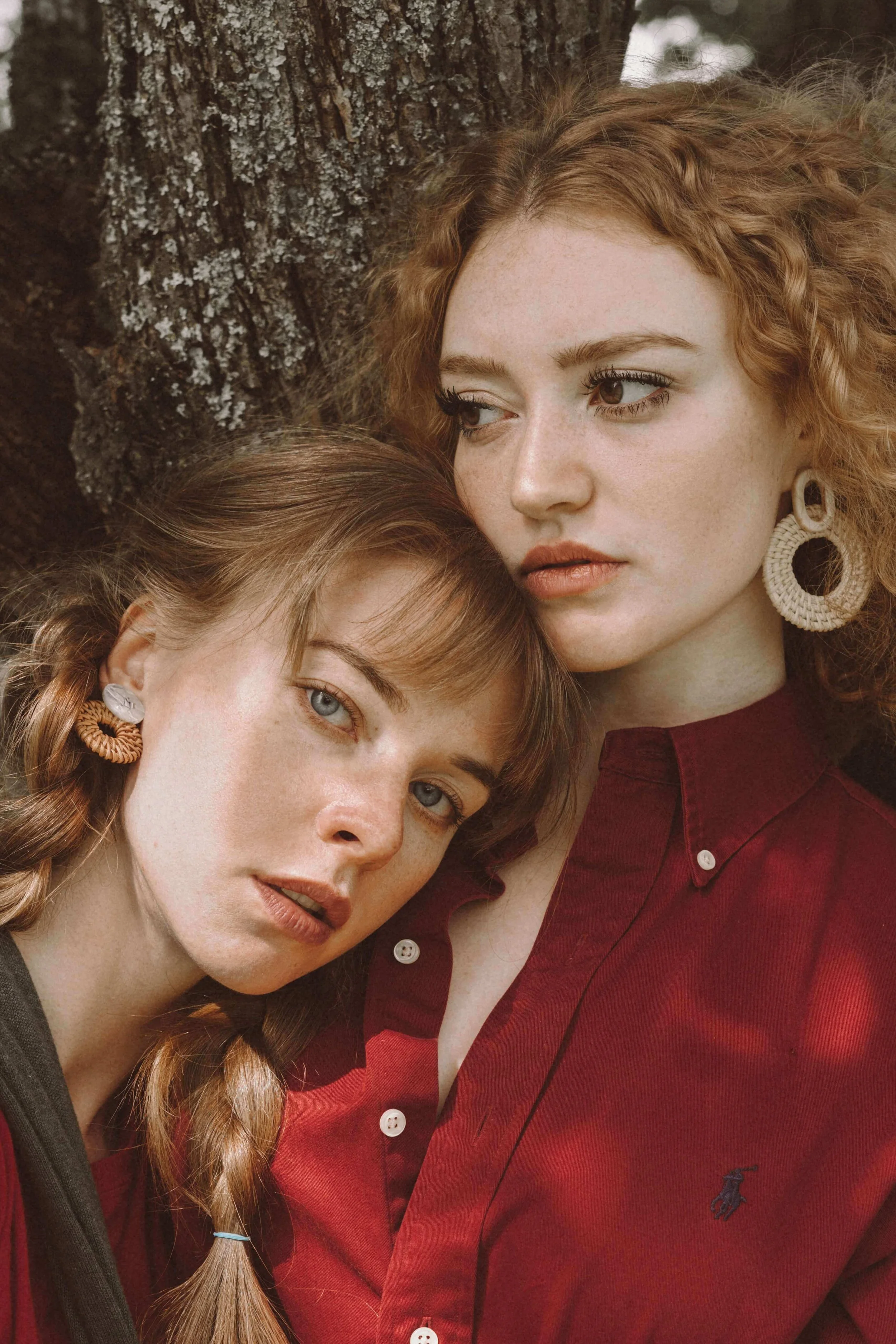 Two women leaning against a tree together