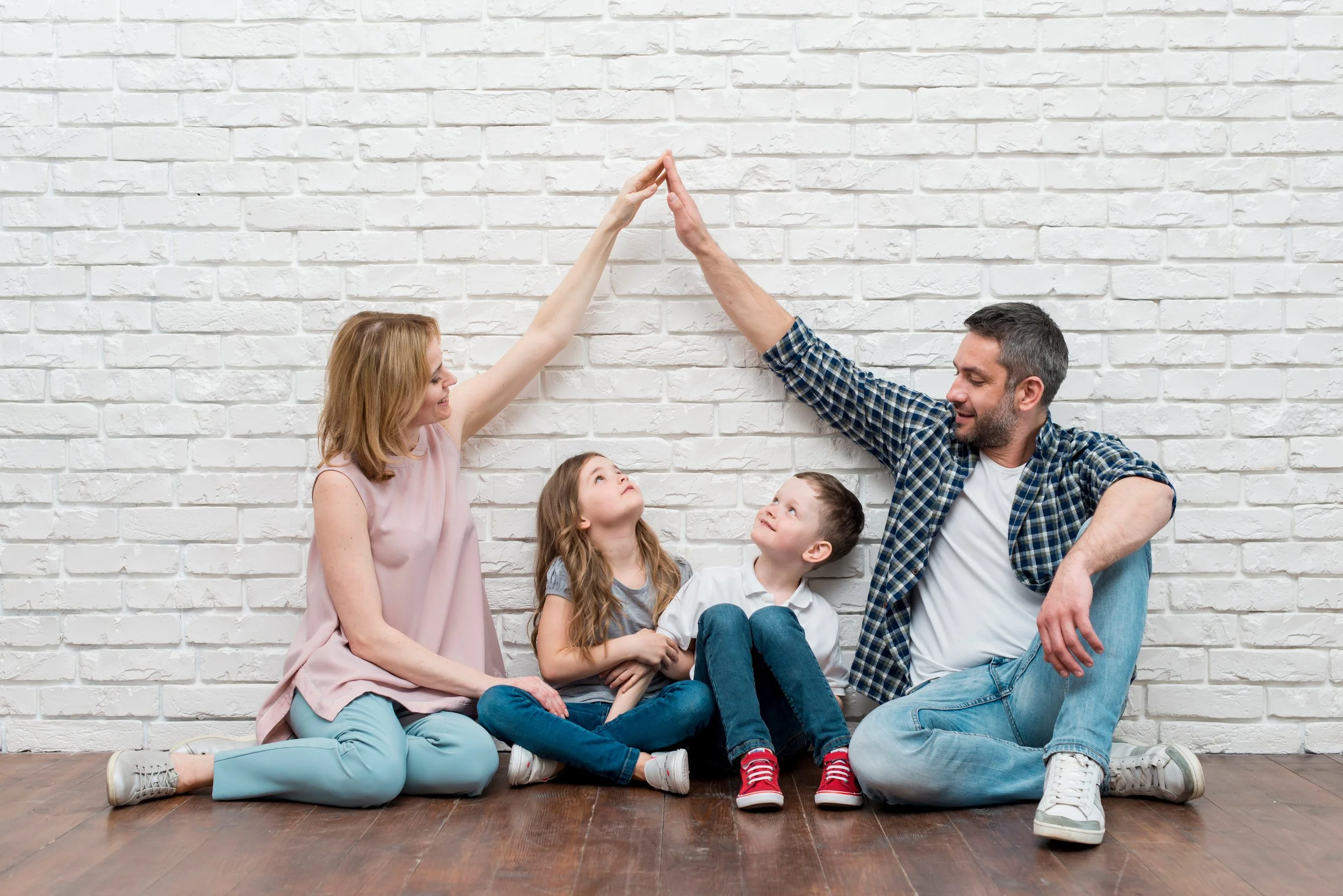 Parents forming a protective roof gesture over their children, representing family mediation and child-focused support by 2Mediate.