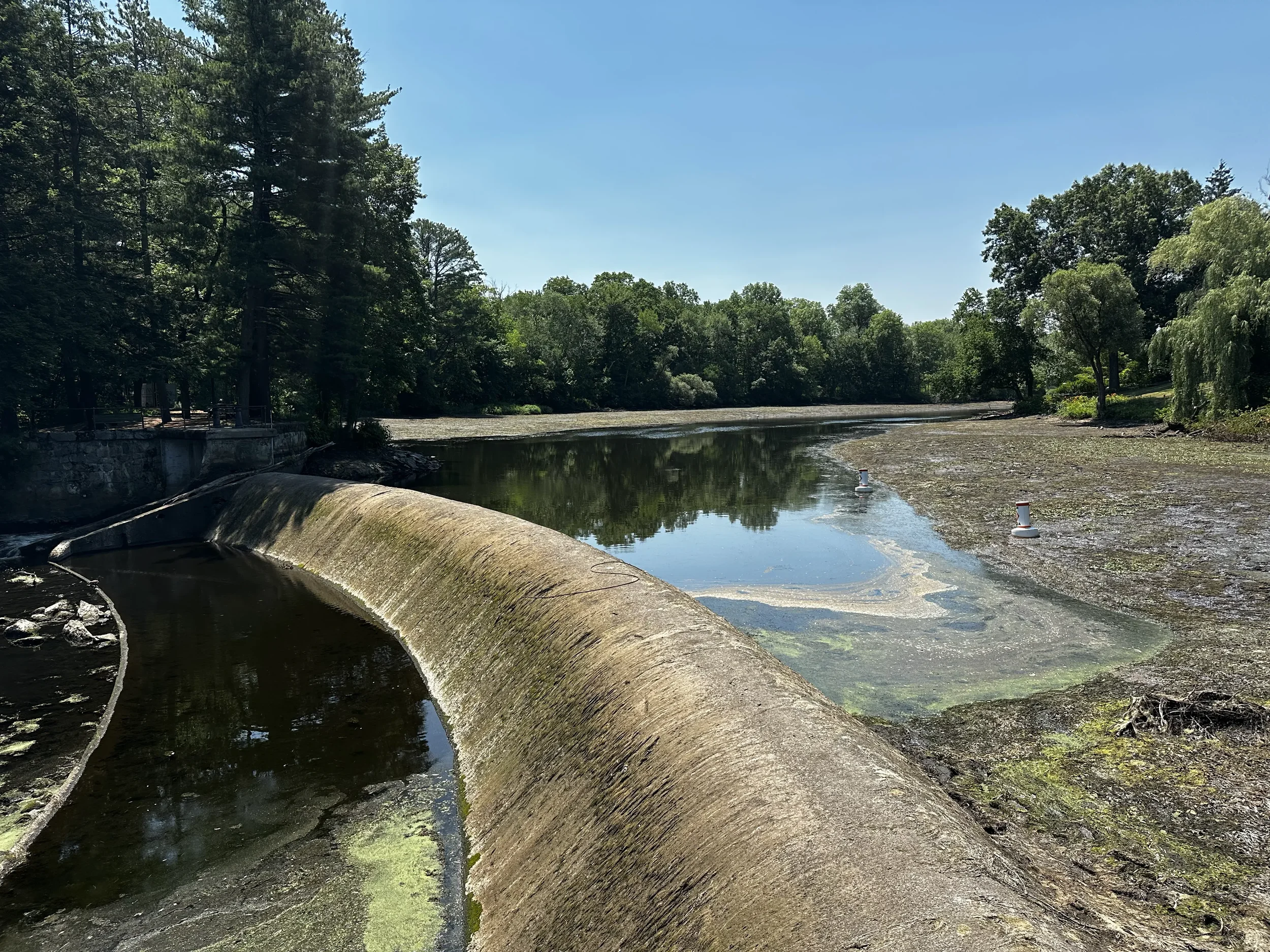  Low water levels at the South Natick Dam, the river bed is visible and there is a small pool of water  