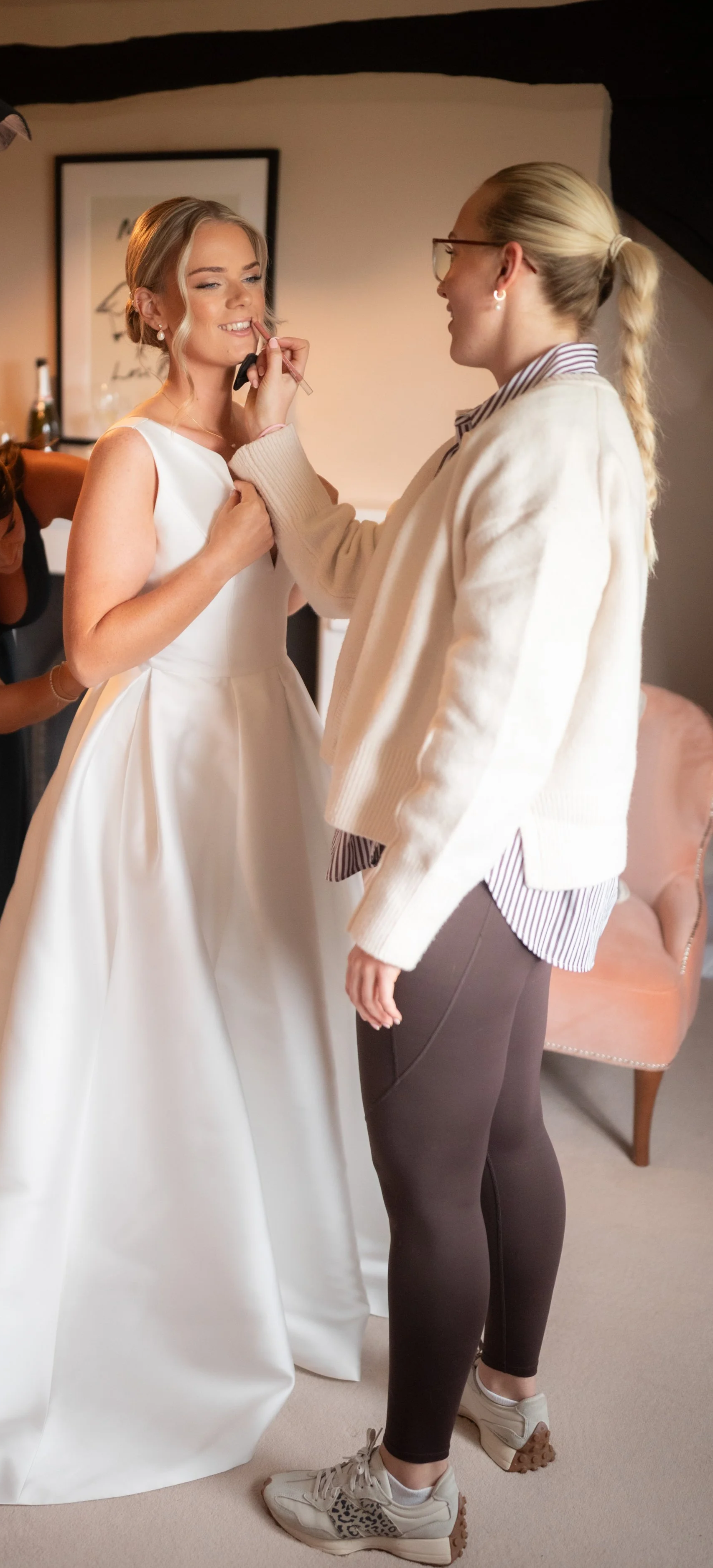 Modern bride getting makeup touch ups before ceremony at Copdock Hall. The bride looks happy, calm and gorgeous with beautiful makeup. The makeup artist is calm and relaxed.