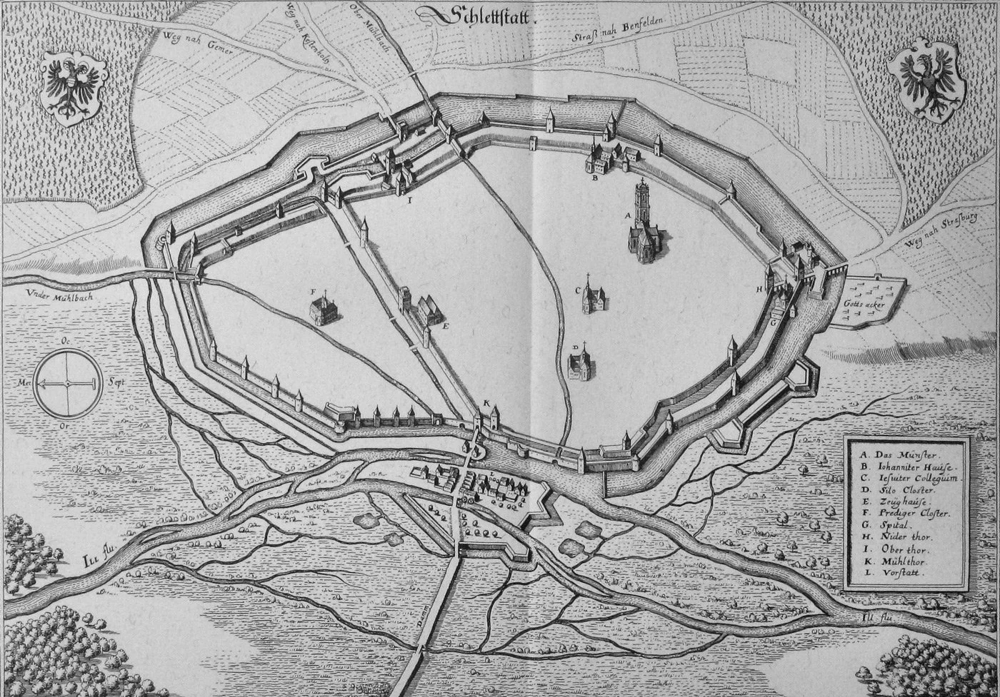 Historical map of a medieval fortress with walls, towers, and buildings, including a church, cloisters, and a gate, surrounded by roads, a river, and farmland. There are crests with a black eagle on either side of the map.