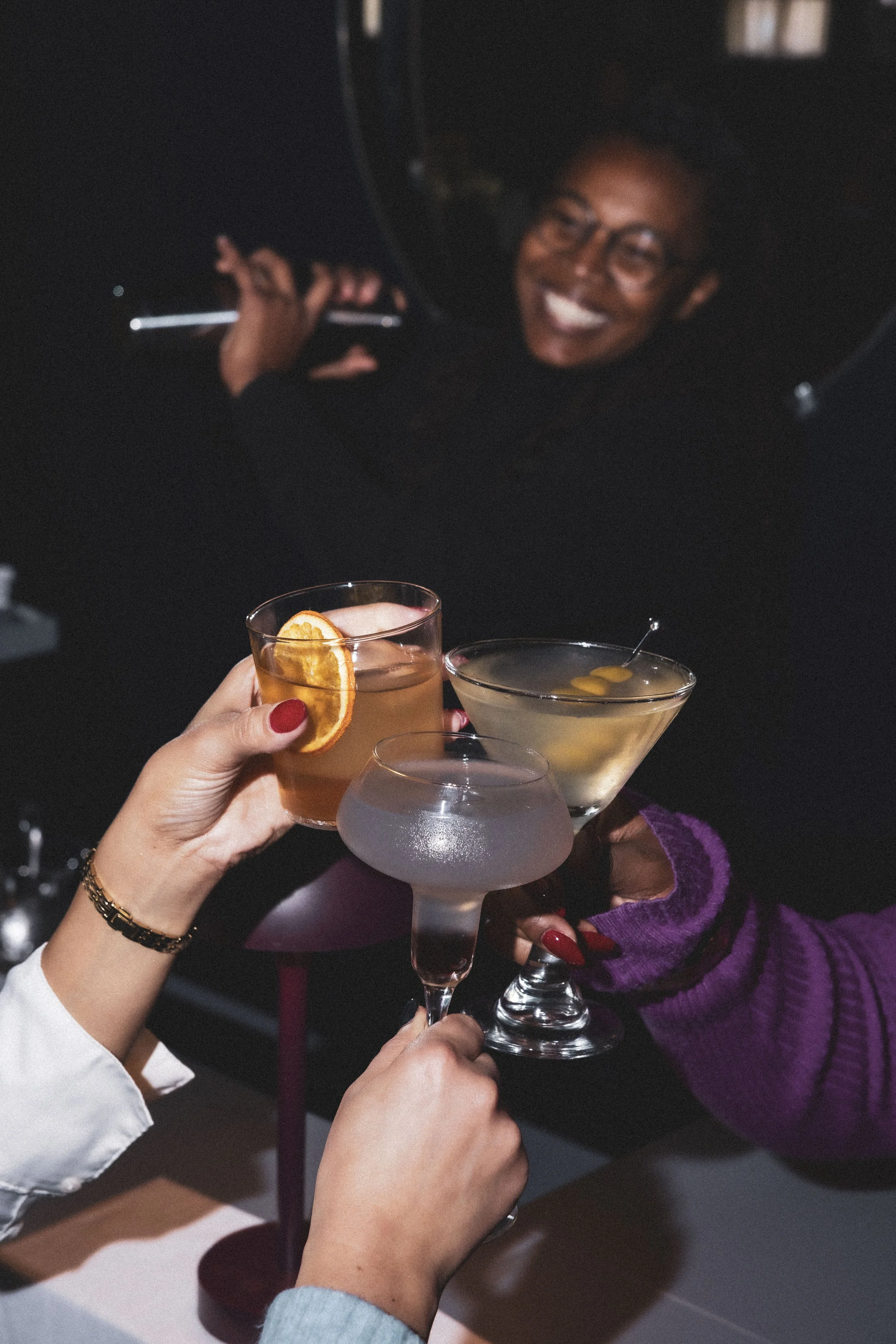 Two glasses with a decorative pattern containing a pink-colored beverage, garnished with grapefruit slices and rosemary sprigs, set on a table with grapefruit halves, rosemary sprigs, and a glass vase with dried branches.