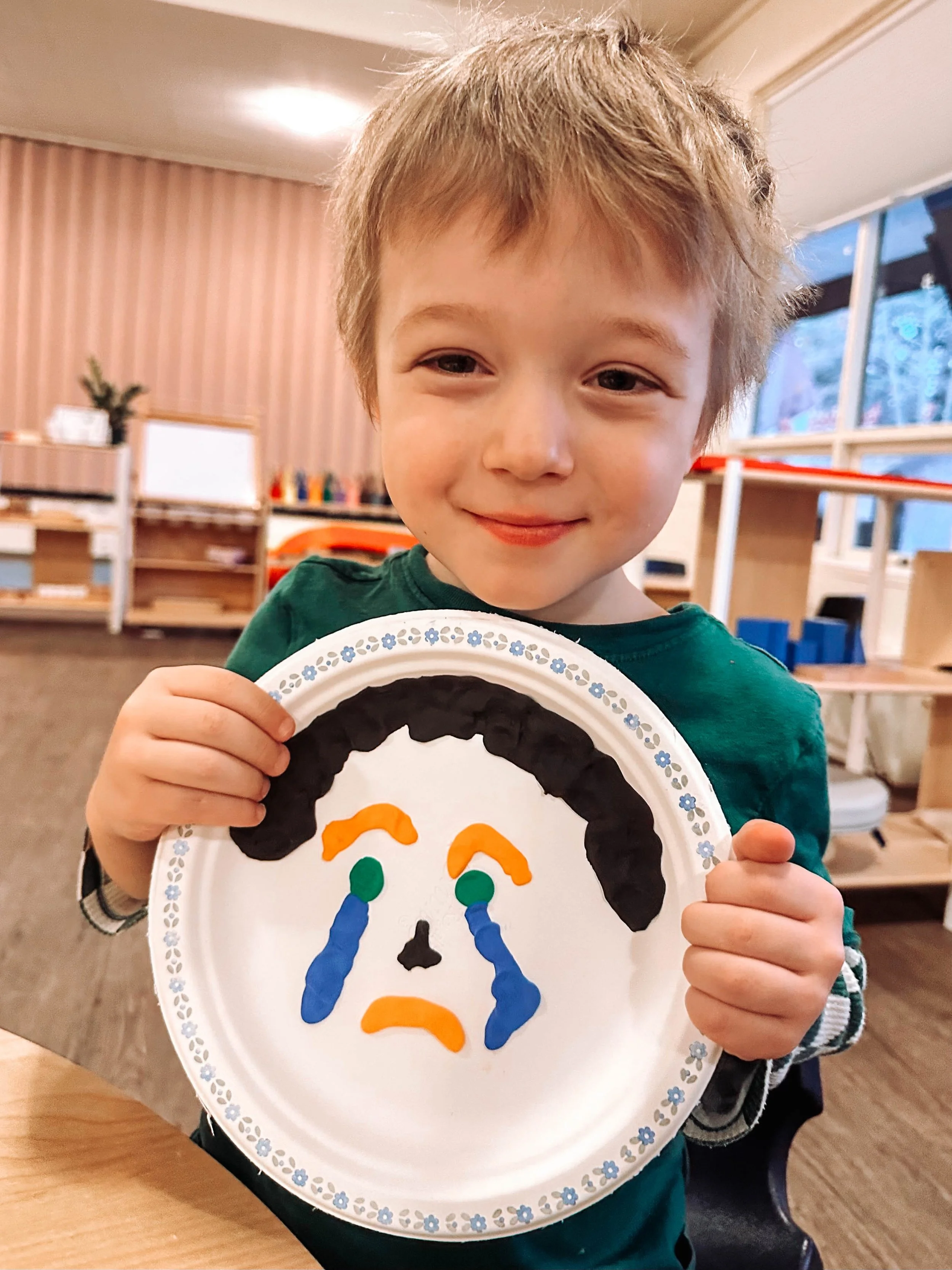 A black and white dog is jumping into the air in front of a brown, white, and black dog, both outdoors on grass with a clear sky in the background.
