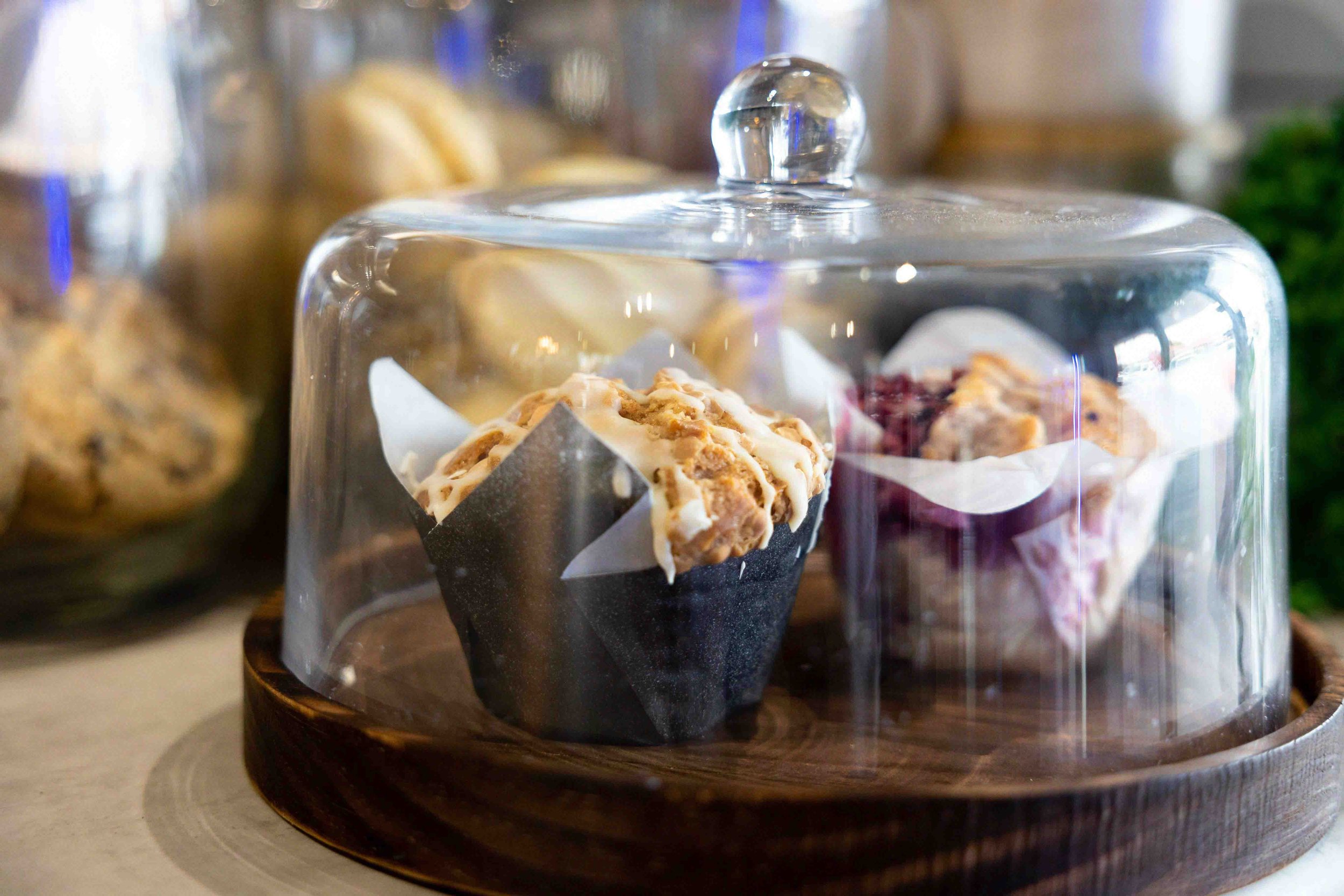 Muffins sitting on a chopping board with a cloche over the top