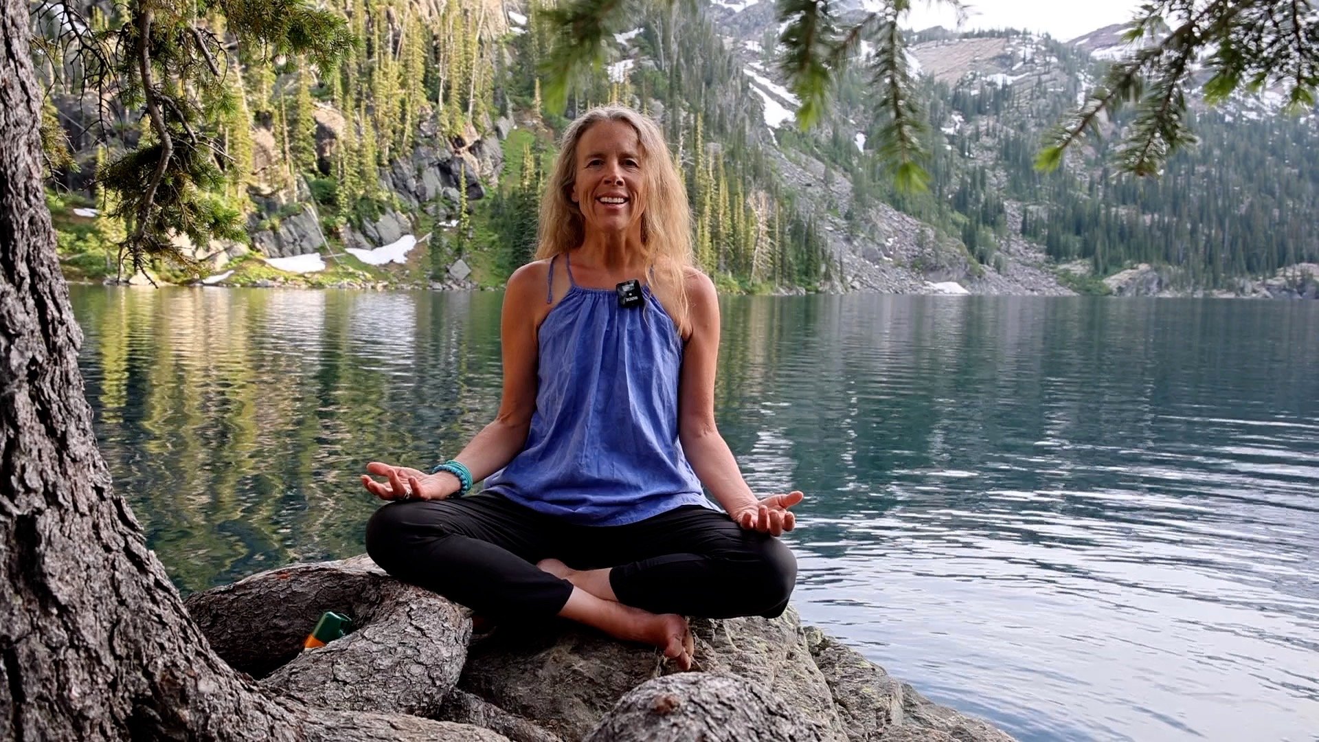 image of Cheyenne in seated mediation with a smile at the lake water